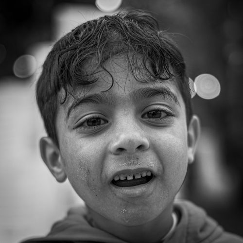 Free Close-up black and white portrait of a young boy with a playful expression outdoors. Stock Photo