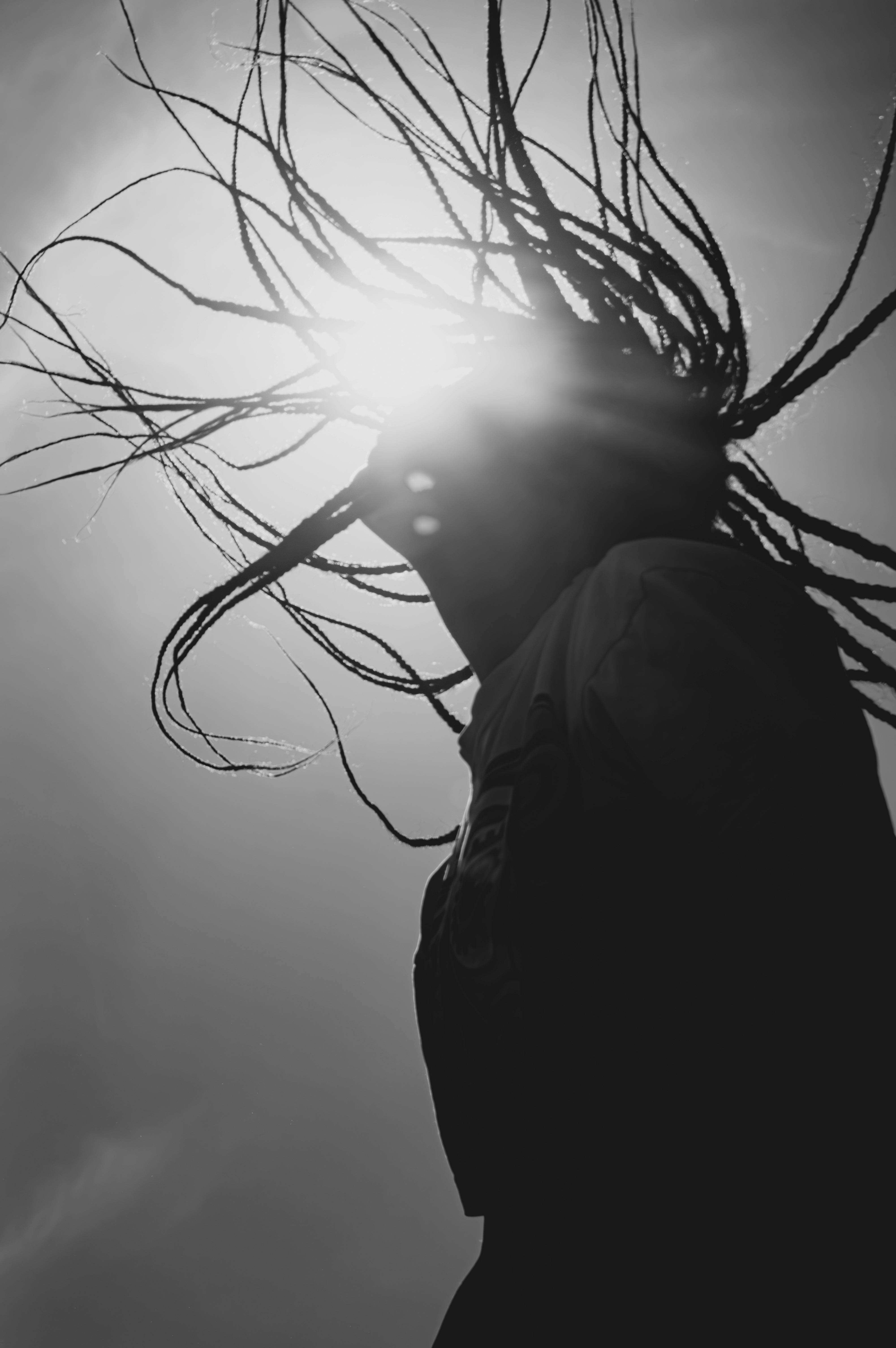 Безкоштовне Художній чорно-білий силует людини з дредами на тлі сонця в Марокко, що підкреслює розширення можливостей та ідентичність. стокове фото