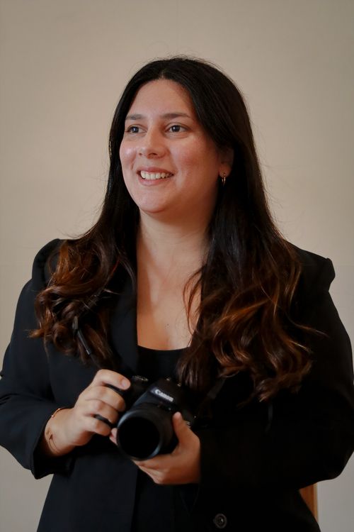 Free Smiling woman holding a camera, dressed in a black outfit. Indoor portrait. Stock Photo