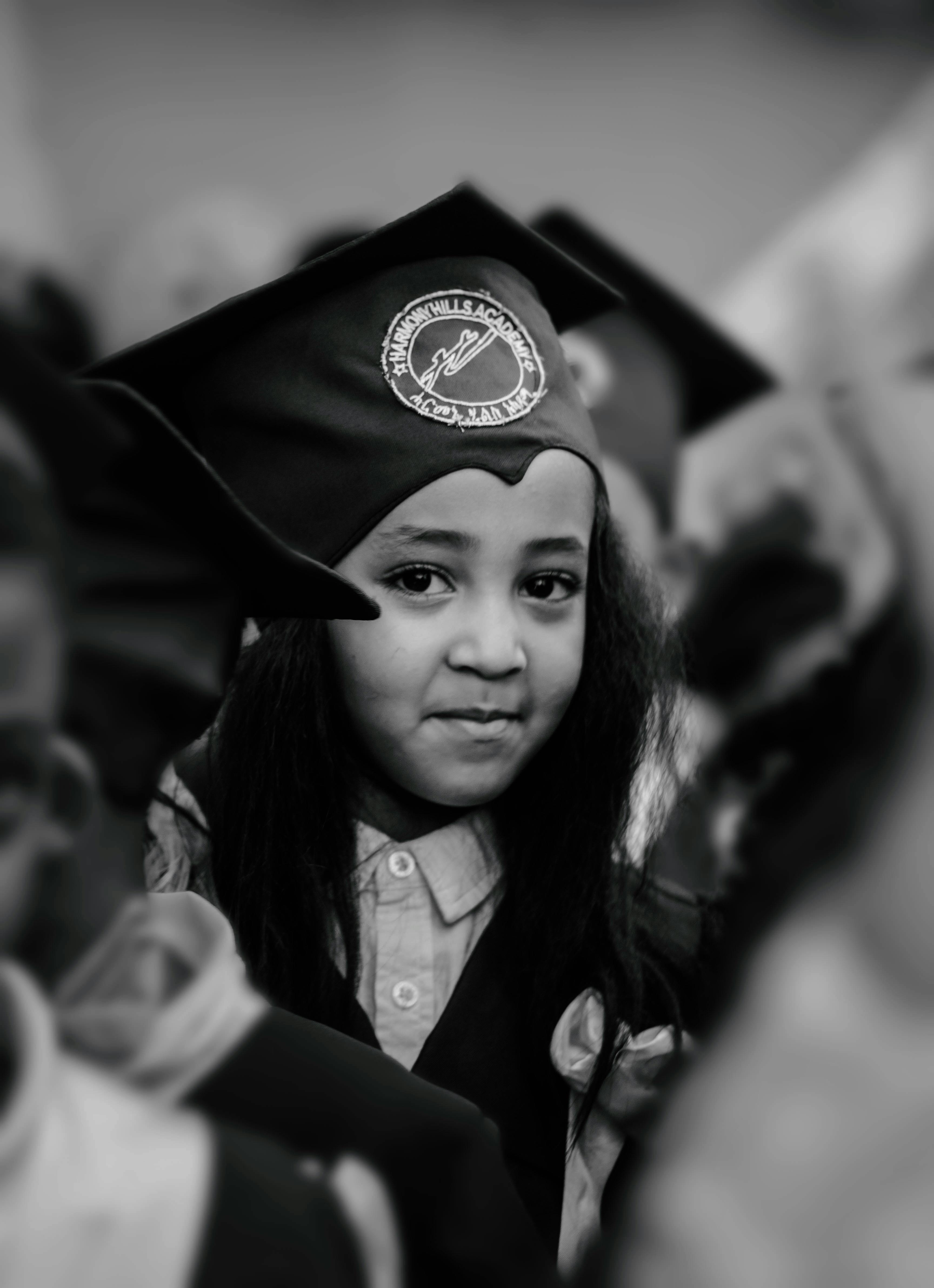 gratis Een kind in afstudeerkleding lacht trots, als symbool van succes en de viering van een mijlpaal in het onderwijs. Stockfoto