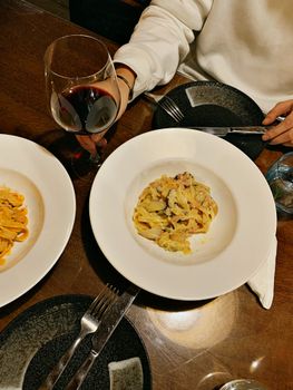 Elegant meal featuring pasta dishes paired with a glass of red wine.