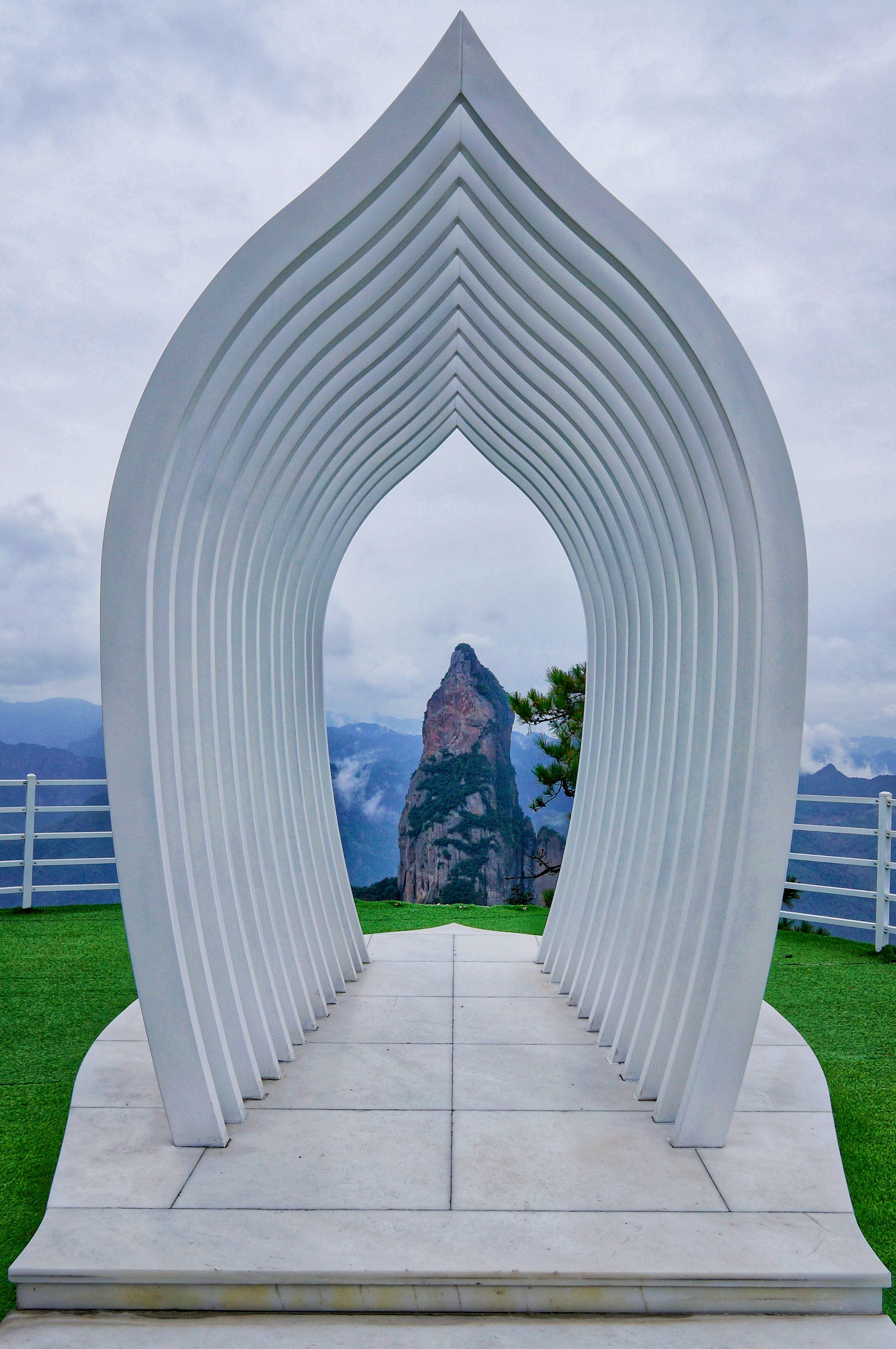 [ColoSach]-white-arch-structure-perfectly-frames-a-distant-mountain-peak-under-a-cloudy-sky.