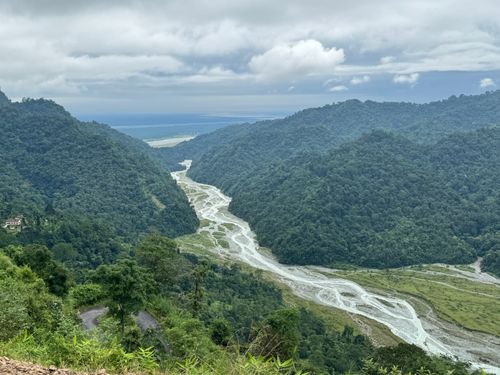 Free A breathtaking view of a mountain river valley with lush greenery under a cloudy sky. Stock Photo
