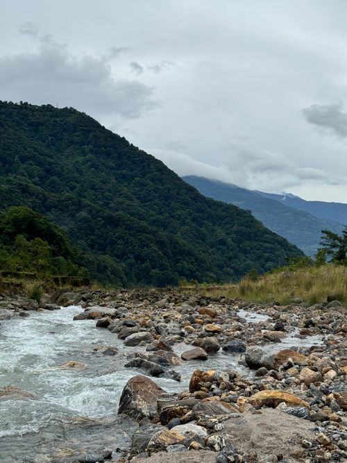 Free Scenic view of a river surrounded by lush green mountains and cloudy sky, creating a peaceful atmosphere. Stock Photo