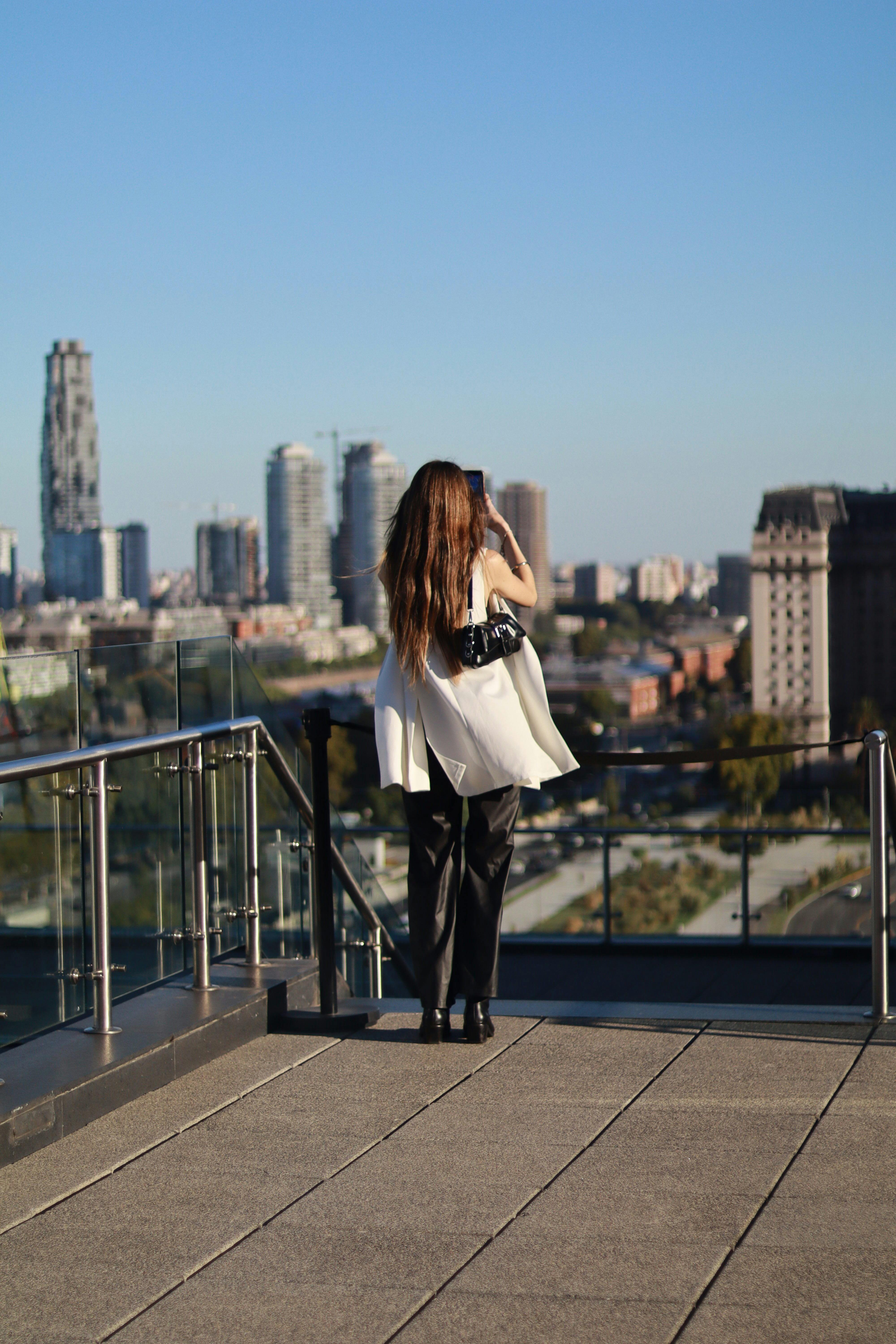 Zadarmo Žena si užíva výhľad na panorámu mesta zo strechy pod jasnou modrou oblohou Fotka z fotobanky