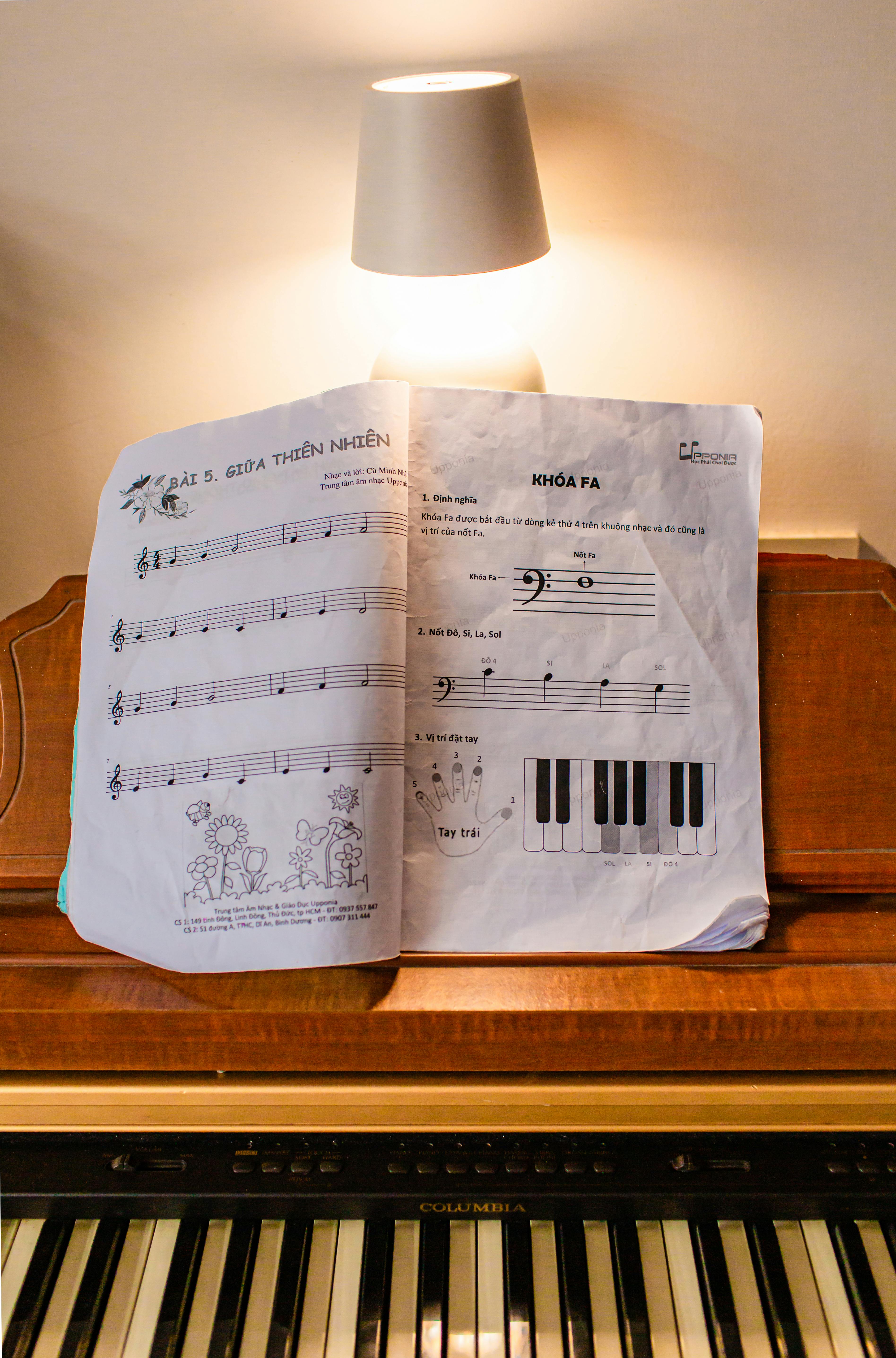 免费 一本摊开的乐谱放在钢琴上，温暖的灯光照亮了它，营造出舒适的练习环境。 素材图片