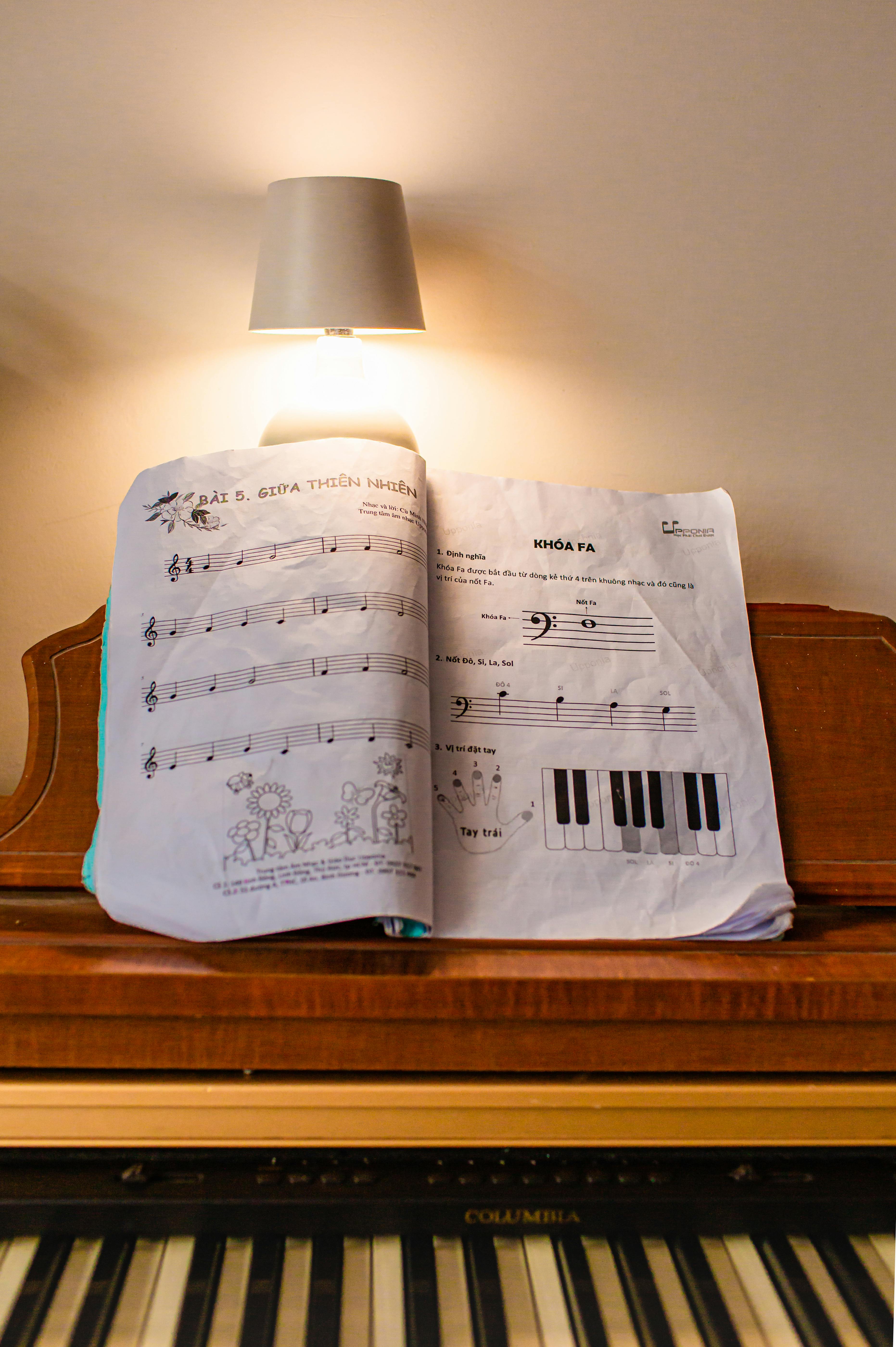 Zadarmo Otvorený notový zväzok na pianíne s tlmenou lampou nad ním vytvára útulnú a teplú atmosféru. Fotka z fotobanky