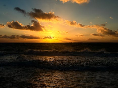 Captivating view of a sunset casting vibrant colors over ocean waves and sky clouds.