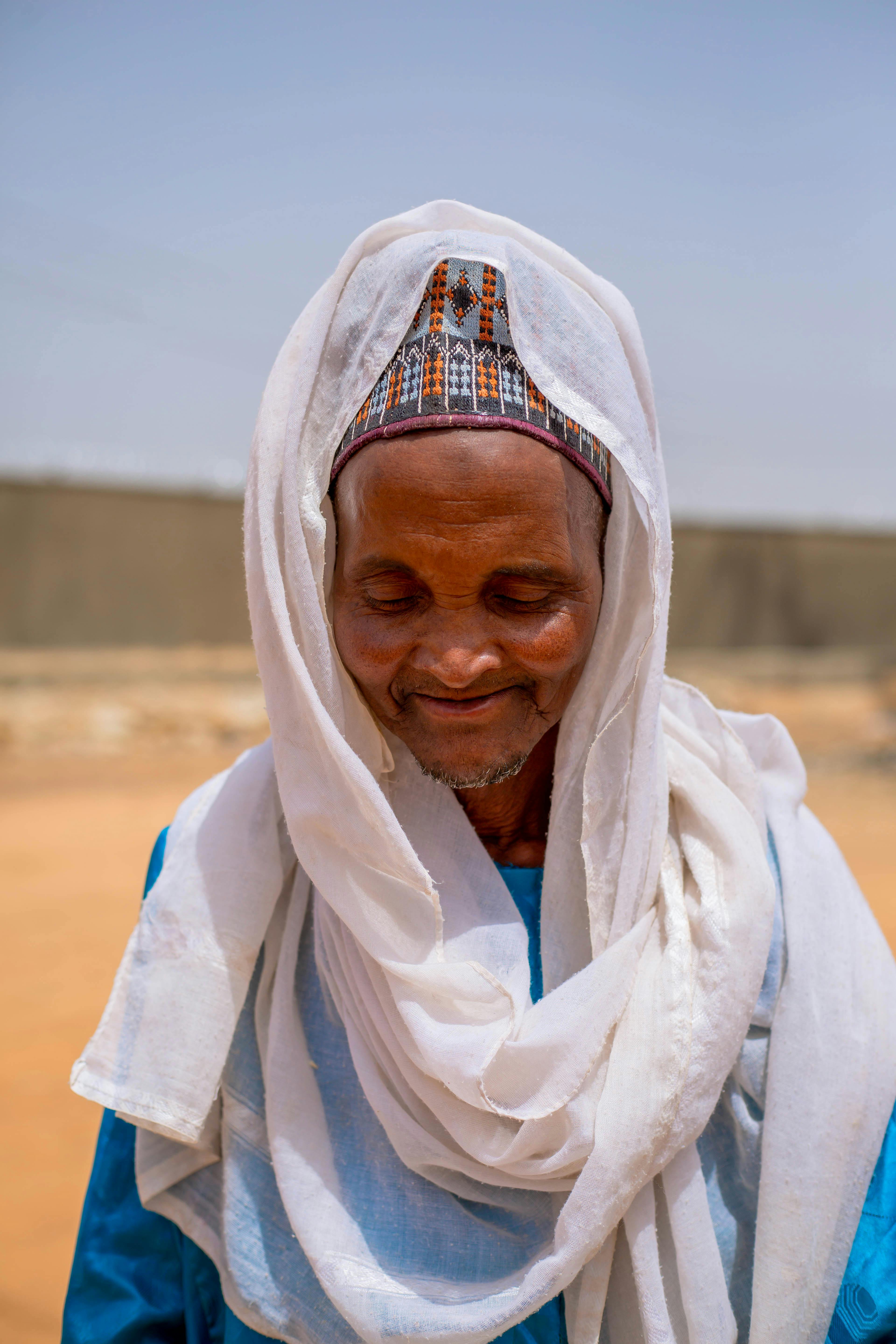 gratis Een traditionele oudere in Kano, Nigeria, draagt ​​een witte tulband en een blauw gewaad in het zonlicht. Stockfoto