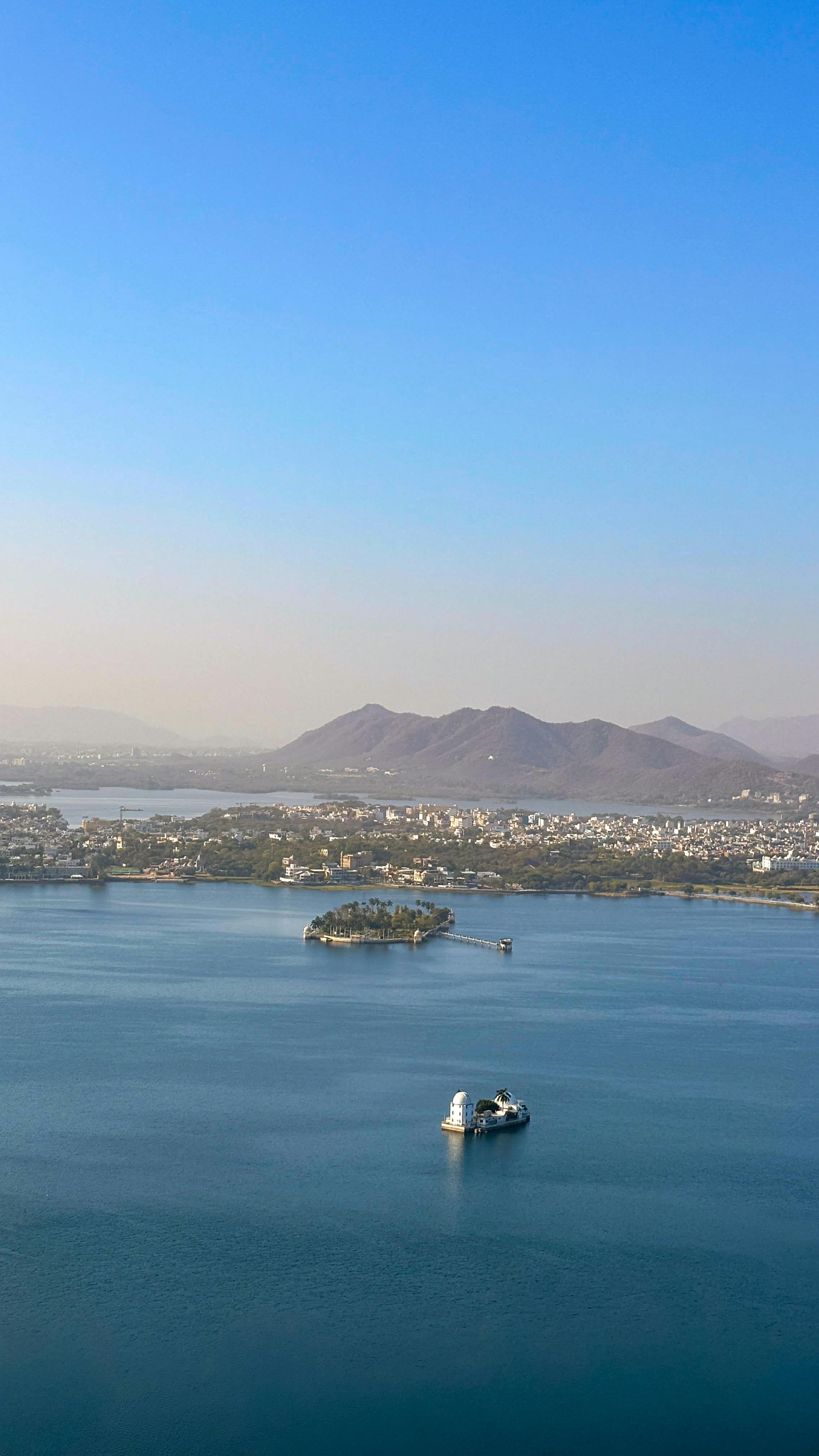 Gratuit Vue aérienne du lac Pichola avec le paysage urbain et les montagnes d'Udaipur, au Rajasthan. Photos
