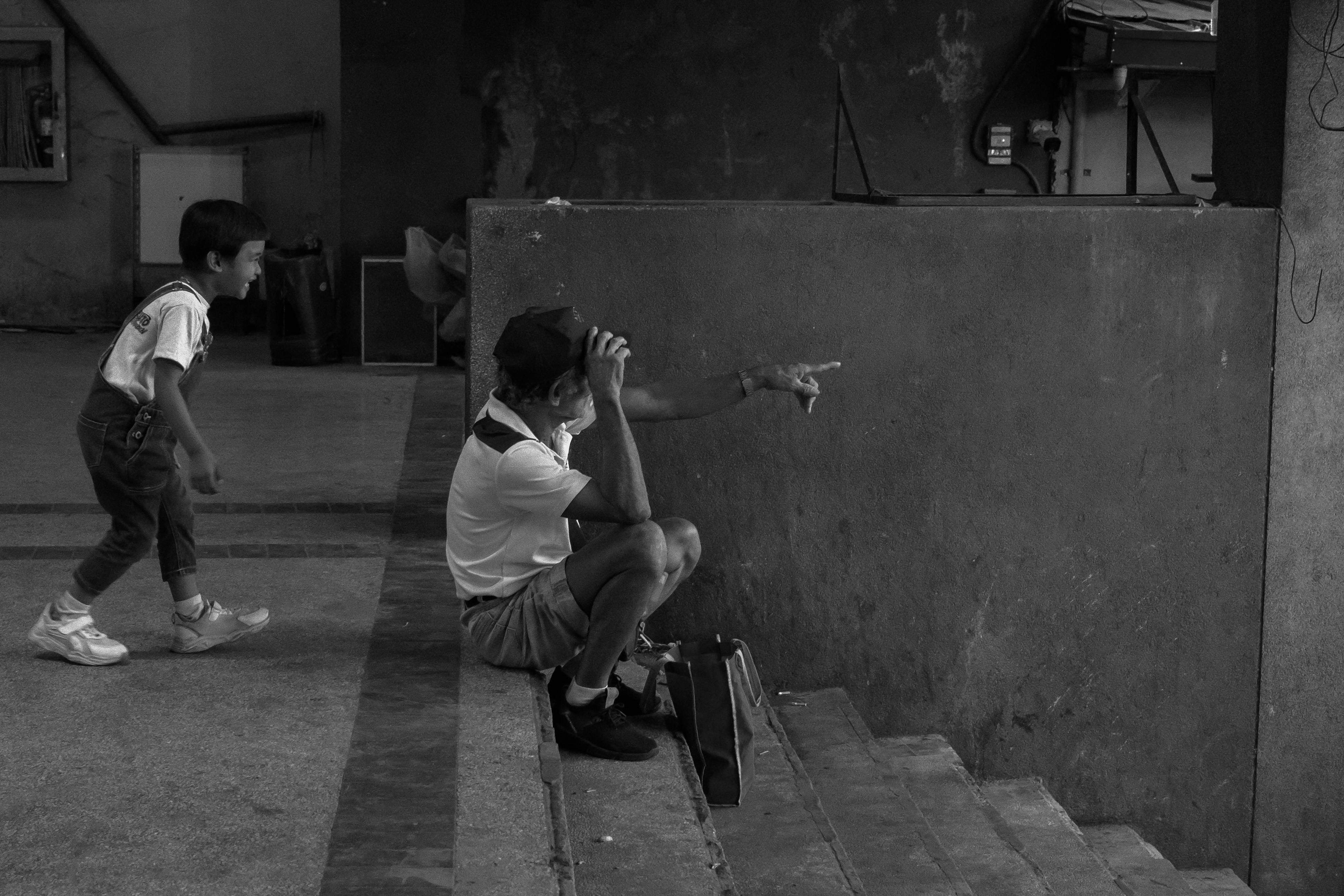 Miễn phí Một bức ảnh đen trắng chụp khoảnh khắc đời thường của một đứa trẻ và một người lớn tuổi đang tương tác trên cầu thang ở Manila, Philippines. Ảnh lưu trữ