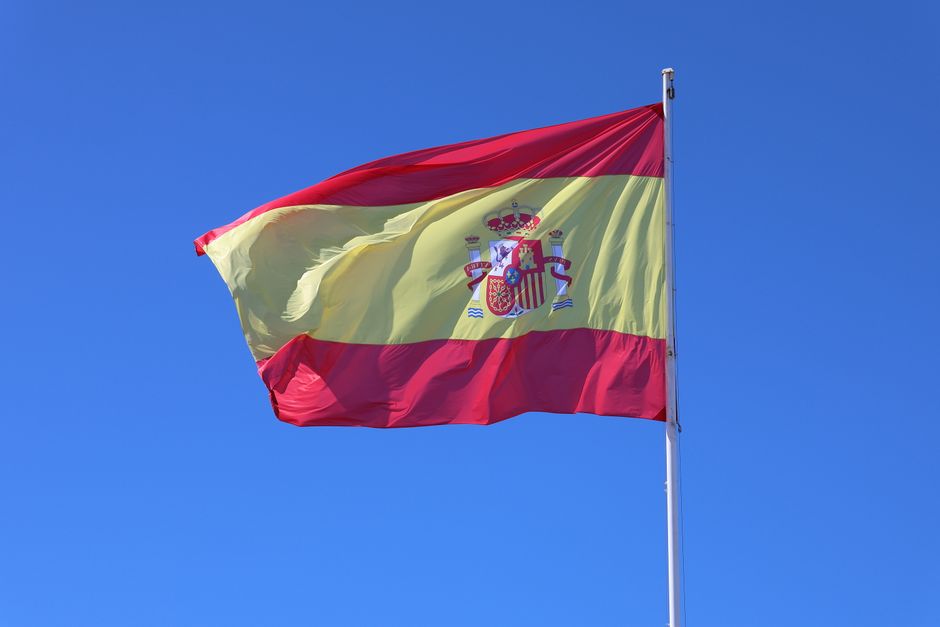Bandera nacional española ondeando contra un cielo azul despejado en Cádiz, Andalucía.
