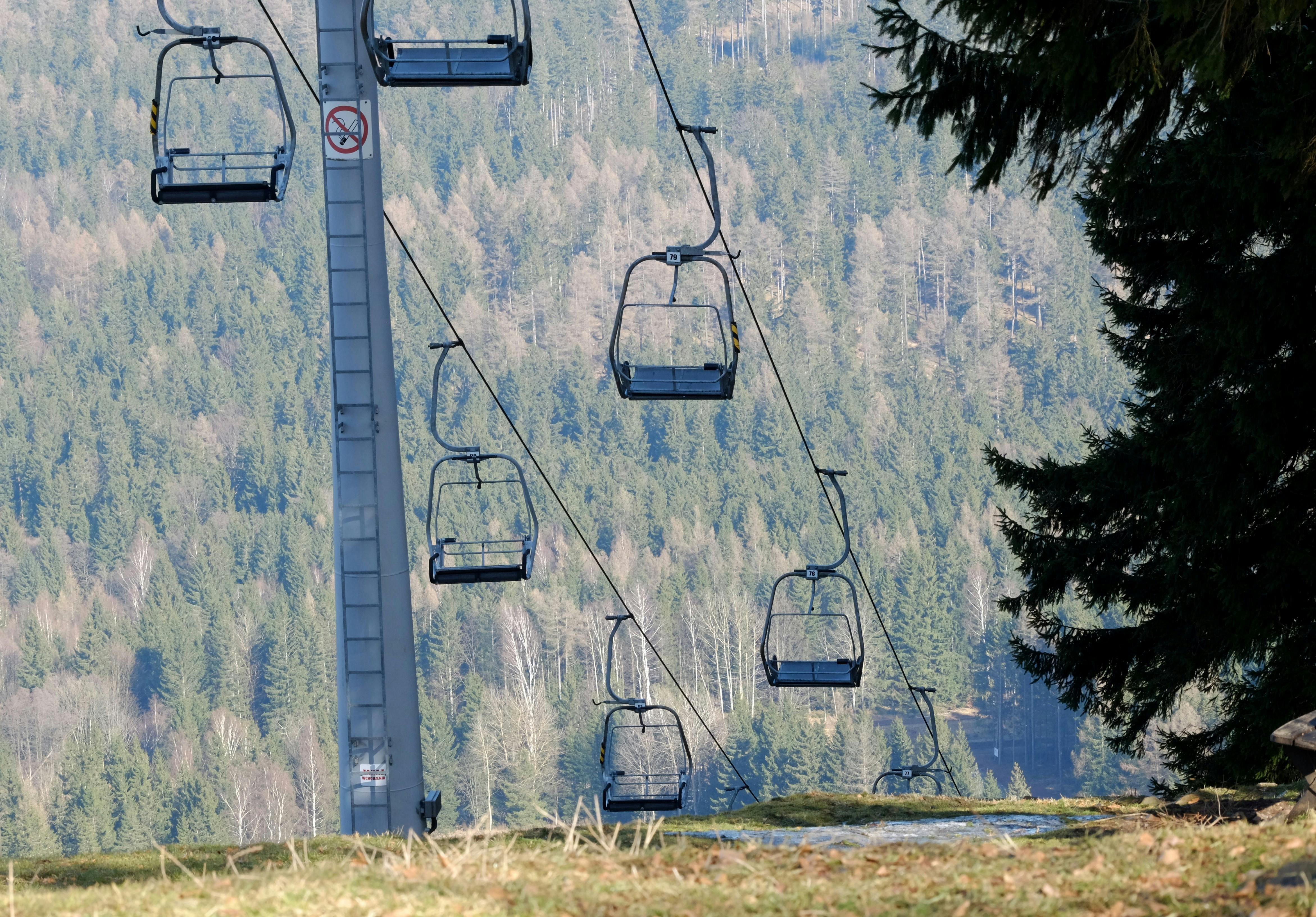 An empty ski lift in a serene mountain setting with lush green forest views.