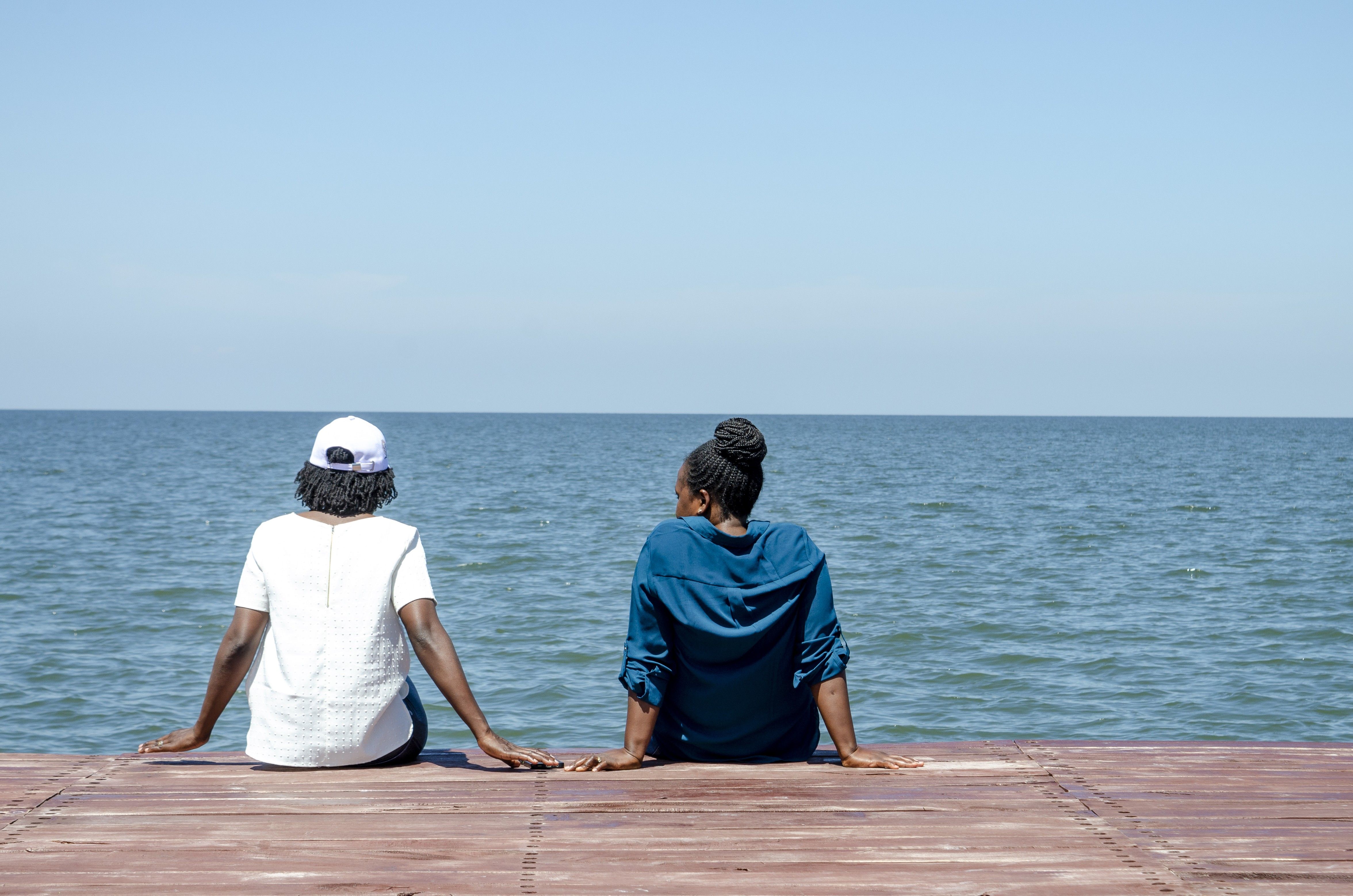 Two people enjoy a tranquil view by the sea on a sunny day.