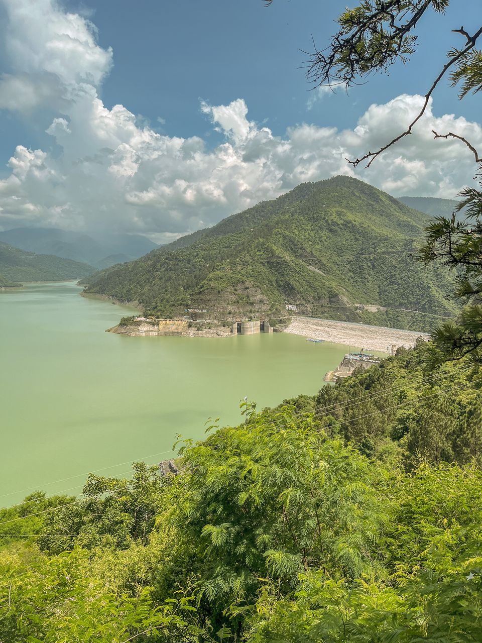 Scenic view of Tehri Dam and surrounding mountains in Uttarakhand, India, under a clear sky.