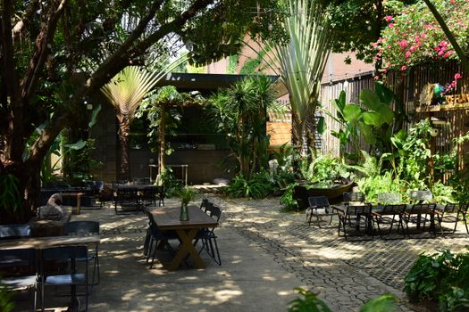 Relax at a tranquil outdoor cafe surrounded by vibrant plants and trees.