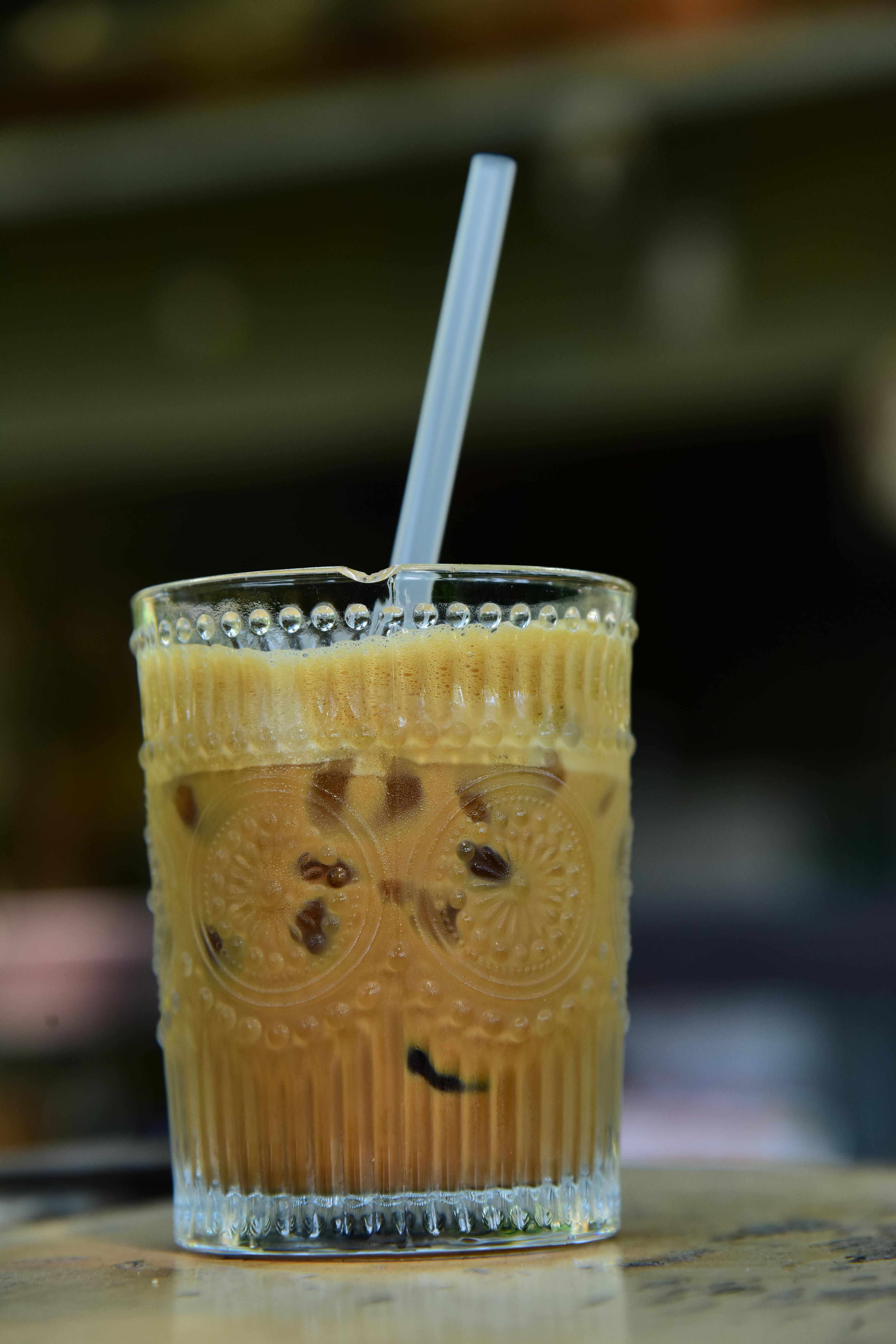 Kostnadsfria Närbild av iskaffe med isbitar och sugrör i ett vintage dekorativt glas. Stock foto