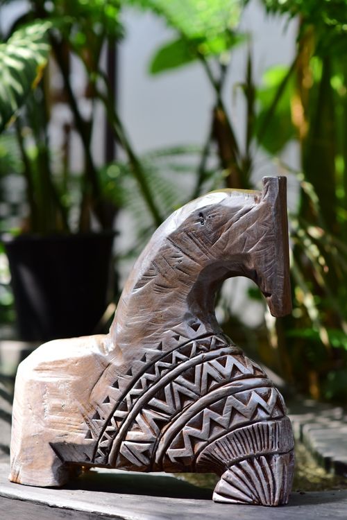 Free Beautiful wooden horse sculpture with tribal patterns in sunlight, surrounded by greenery. Stock Photo