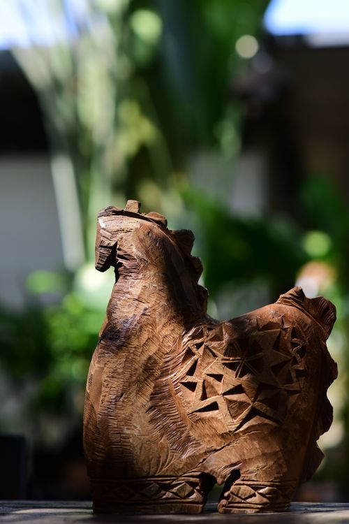 Free A beautifully carved wooden animal sculpture with intricate patterns, set outdoors in a natural environment. Stock Photo