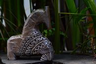 A detailed wooden horse sculpture with tribal patterns in a lush outdoor garden.