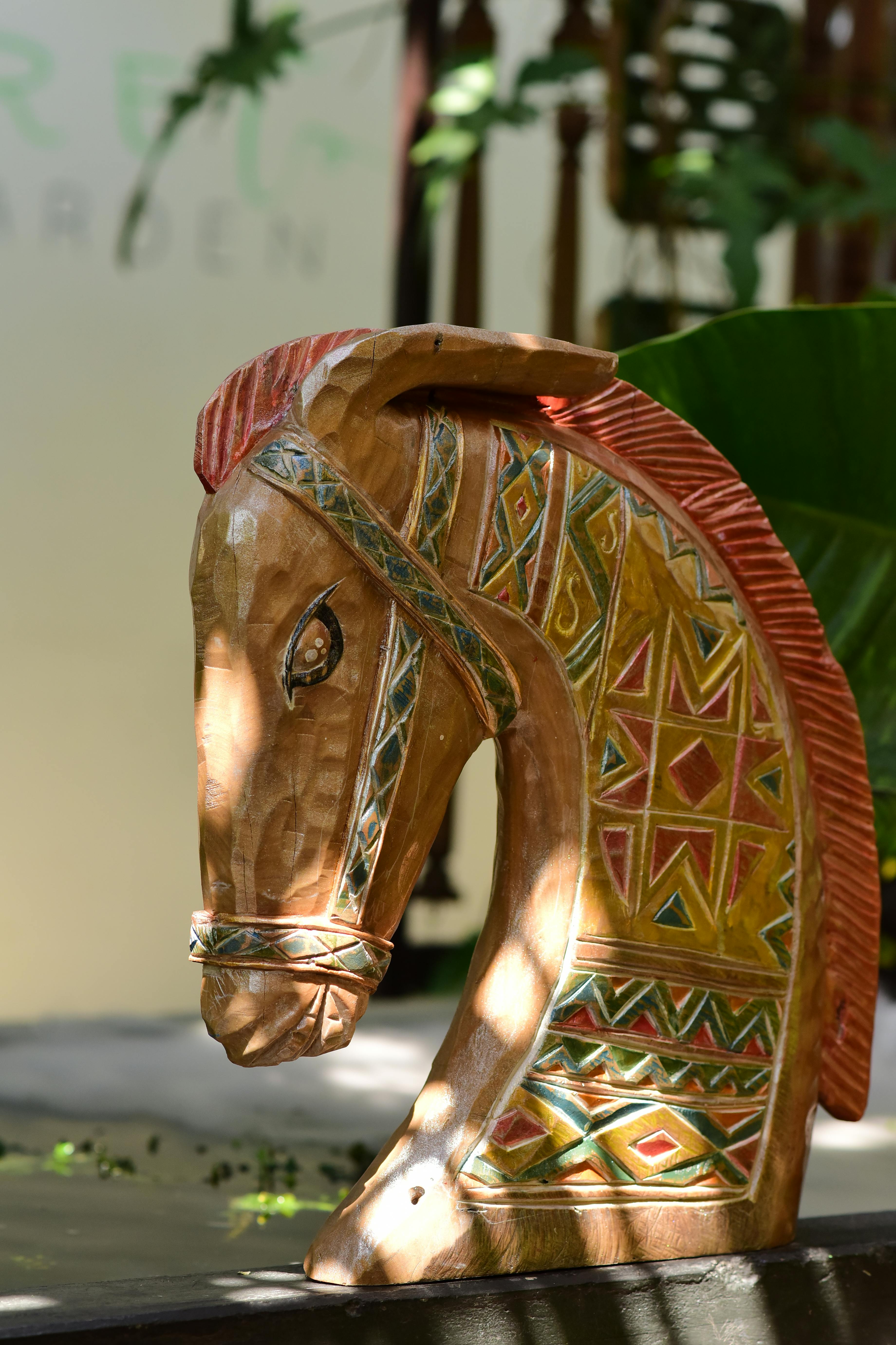 bezplatná Detailně vyřezávaná dřevěná koňská hlava s kmenovými vzory, zalitá přirozeným světlem. Základová fotografie