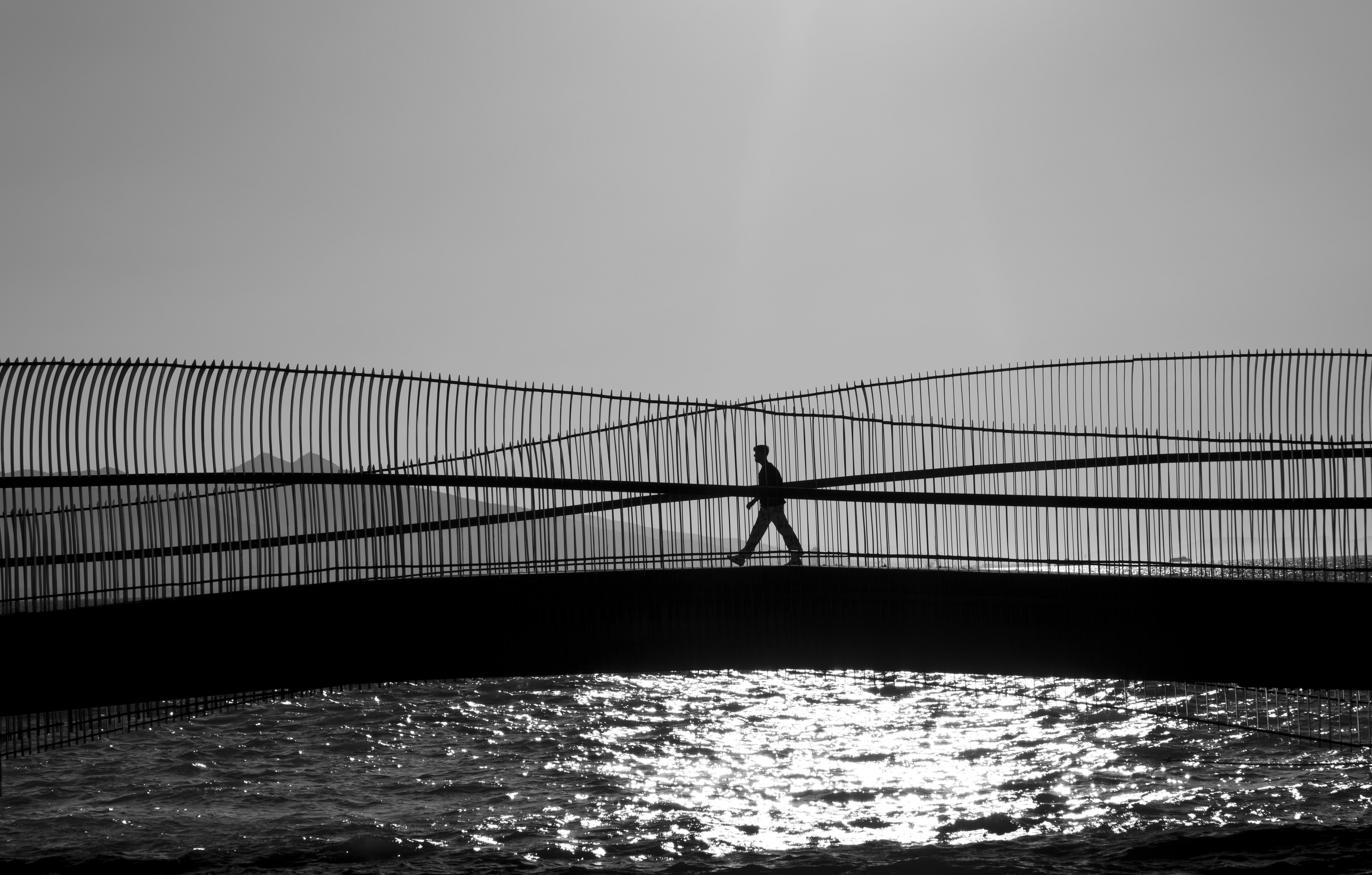 免費 白天，一張黑白照片，展現了一個身影走過一座獨特的橋樑。 圖庫相片