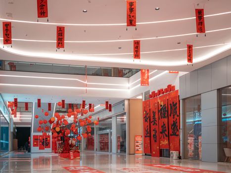 Indoor view of a shopping mall with vibrant red Chinese New Year decorations and banners.