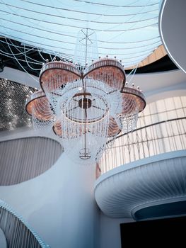 A luxurious chandelier elegantly hangs in a modern, stylish interior with architectural details.