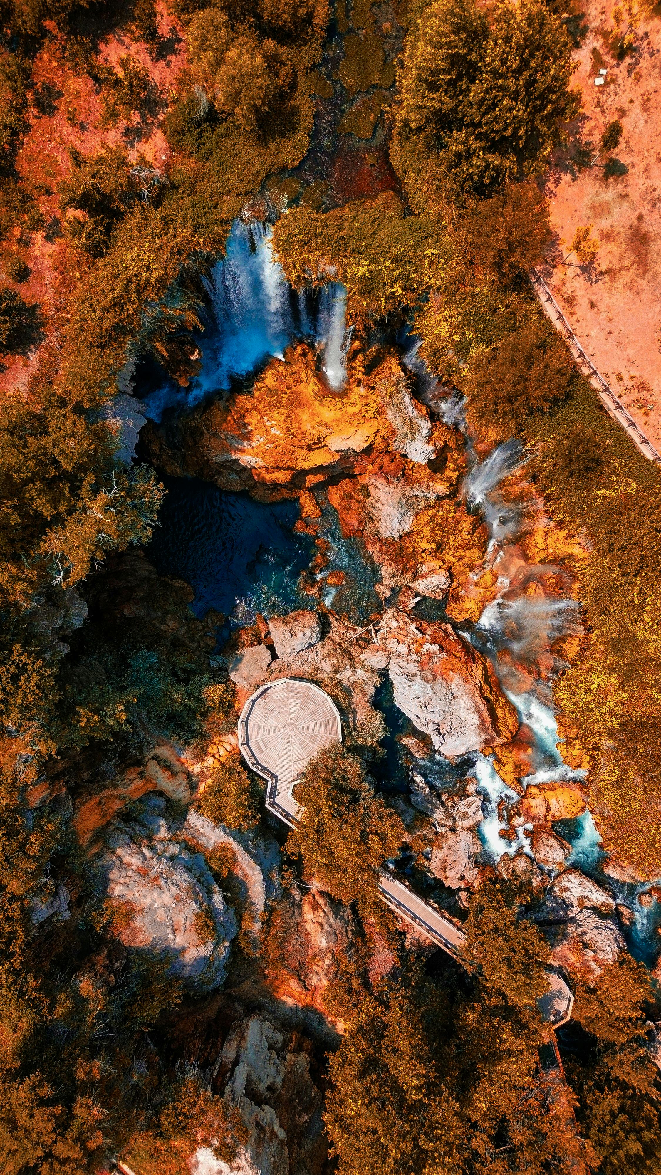 bezplatná Majestátní letecký pohled na vodopád obklopený zářivým podzimním listím a skalnatým terénem. Základová fotografie