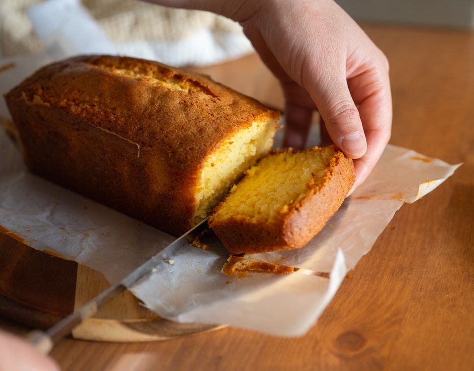 Free Close-up of a hand slicing a homemade pound cake, capturing the golden crust and soft texture. Stock Photo