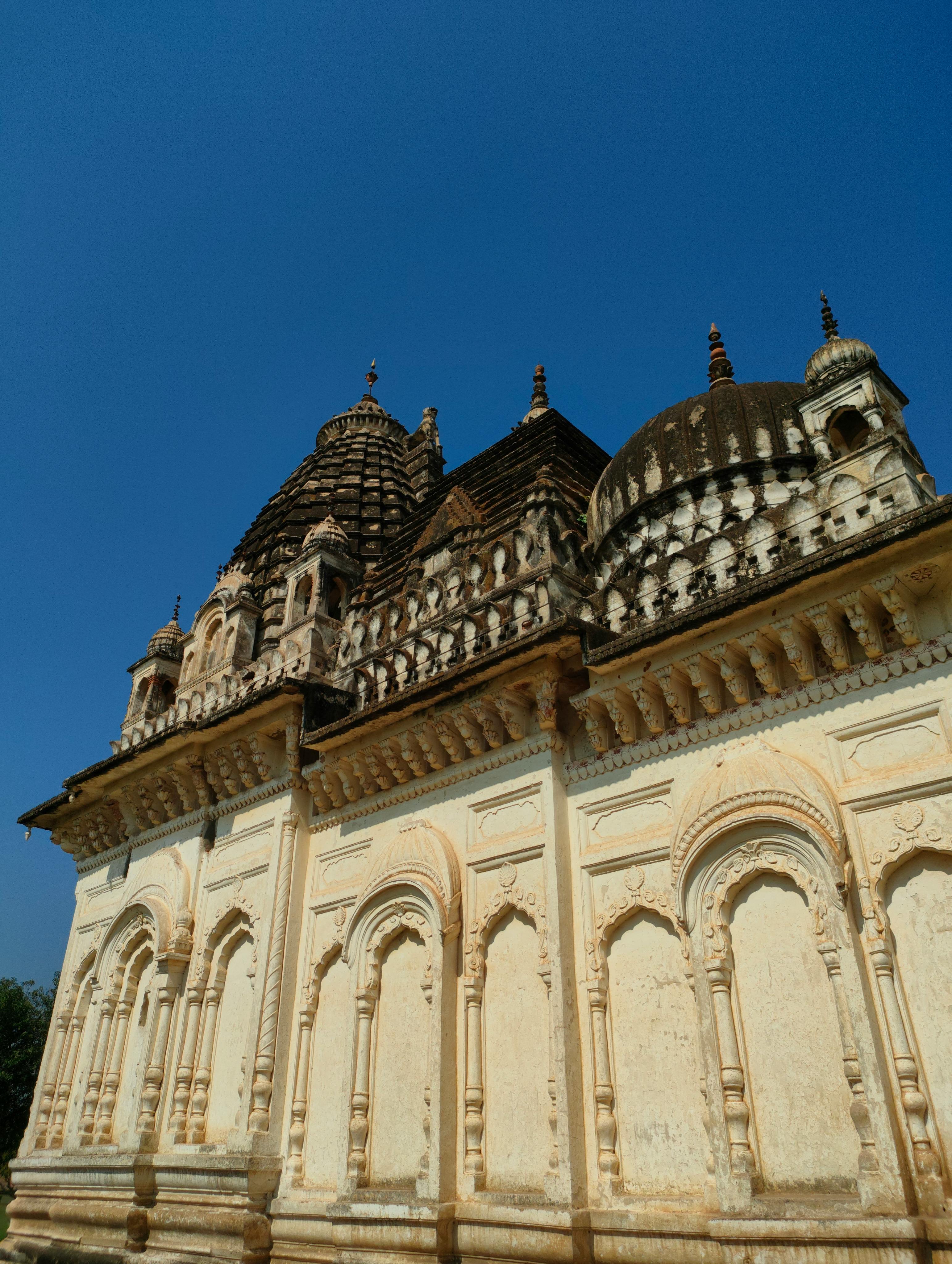 Bezpłatne Odkryj tę oszałamiającą starożytną świątynię w Khajuraho, której kunsztowna architektura kontrastuje z czystym, błękitnym niebem. Zdjęcie z galerii