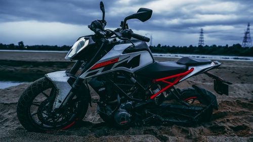 Free A sleek black and white sport motorcycle parked on a sandy beach during twilight. Stock Photo