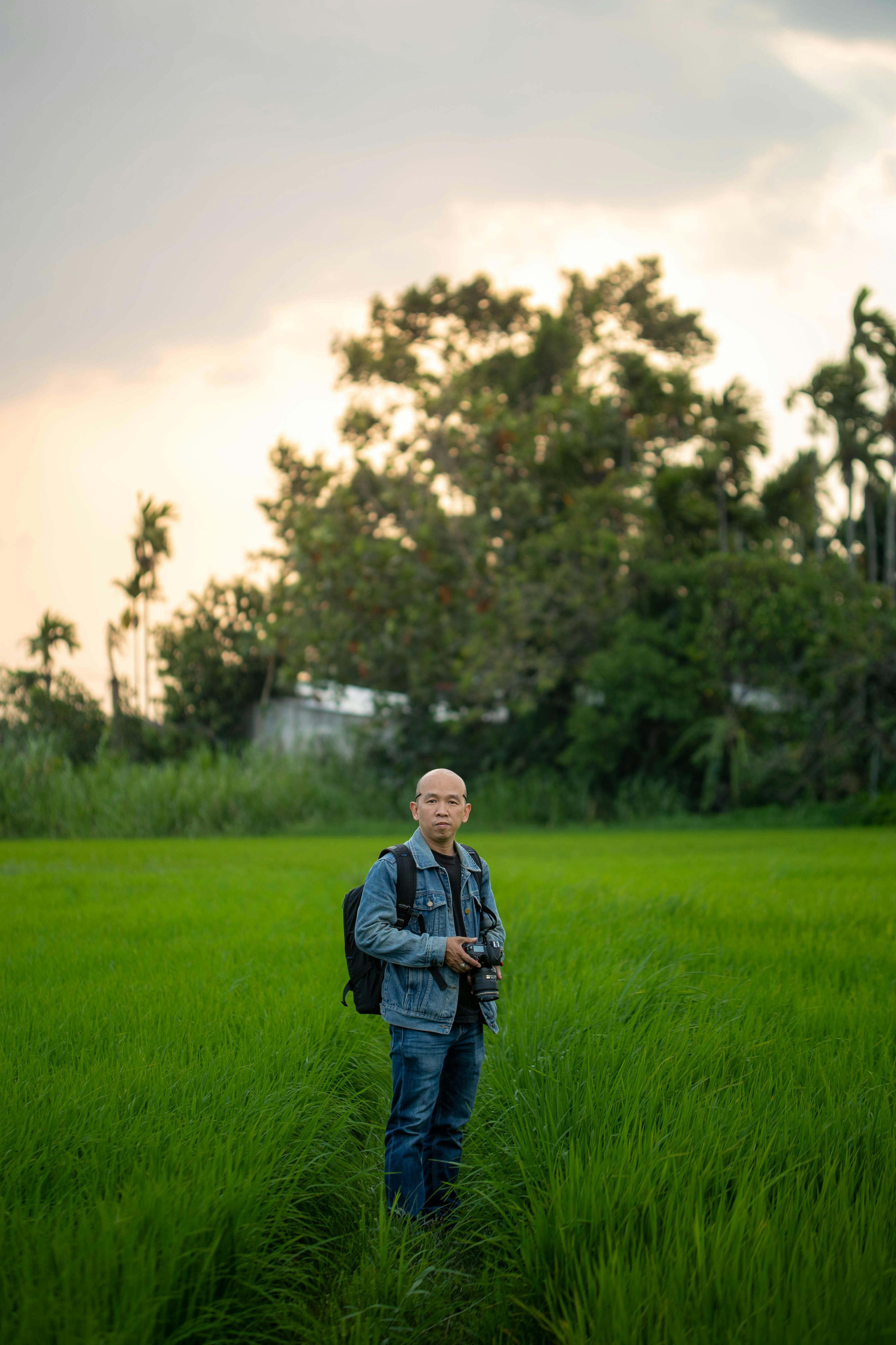 gratis Een fotograaf met een camera in een schilderachtig, groen rijstveld bij zonsondergang. Stockfoto