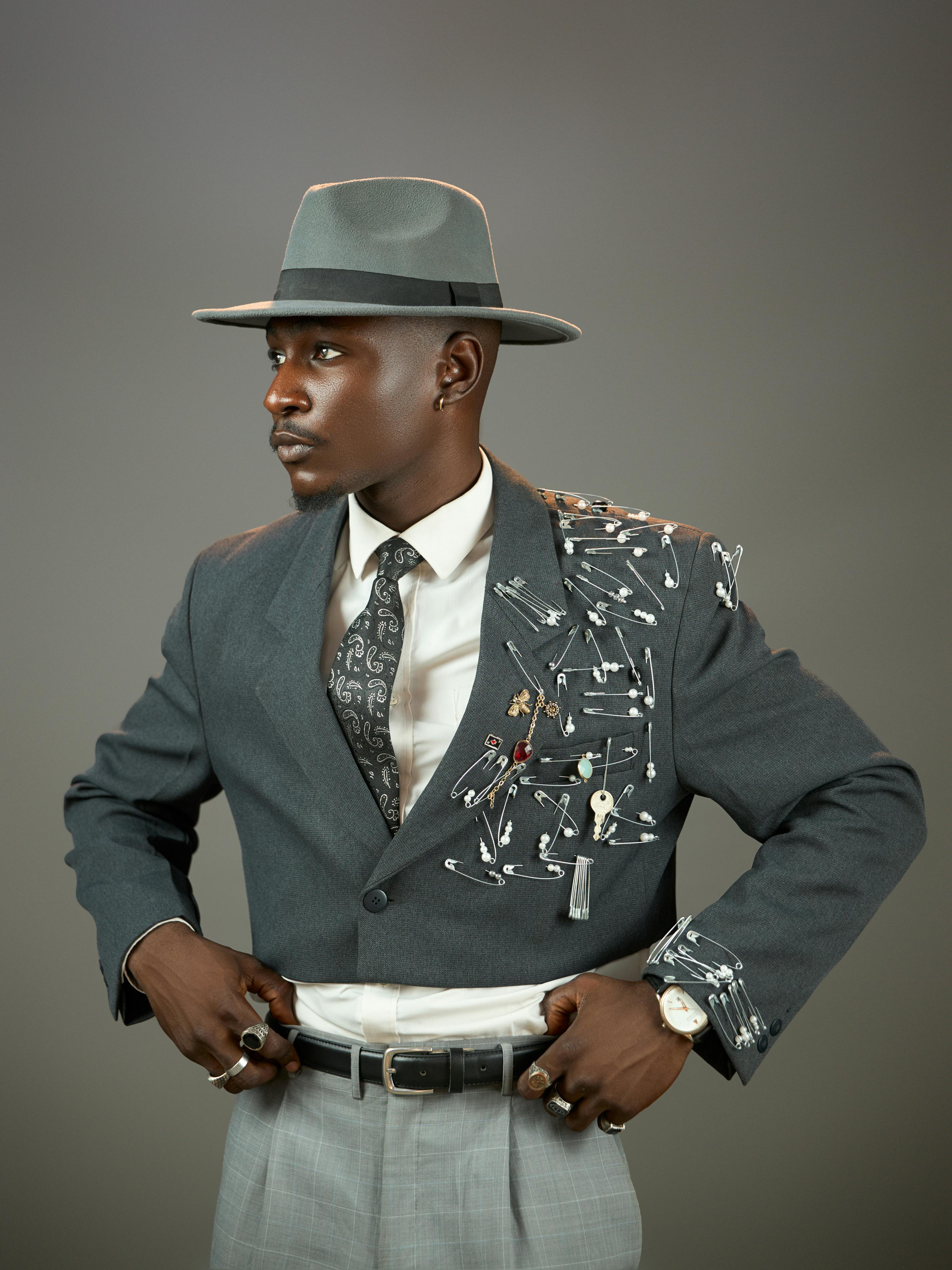 免费 一位时尚男士身着一套配饰独特的西装和帽子，风格现代而富有艺术气息。 素材图片