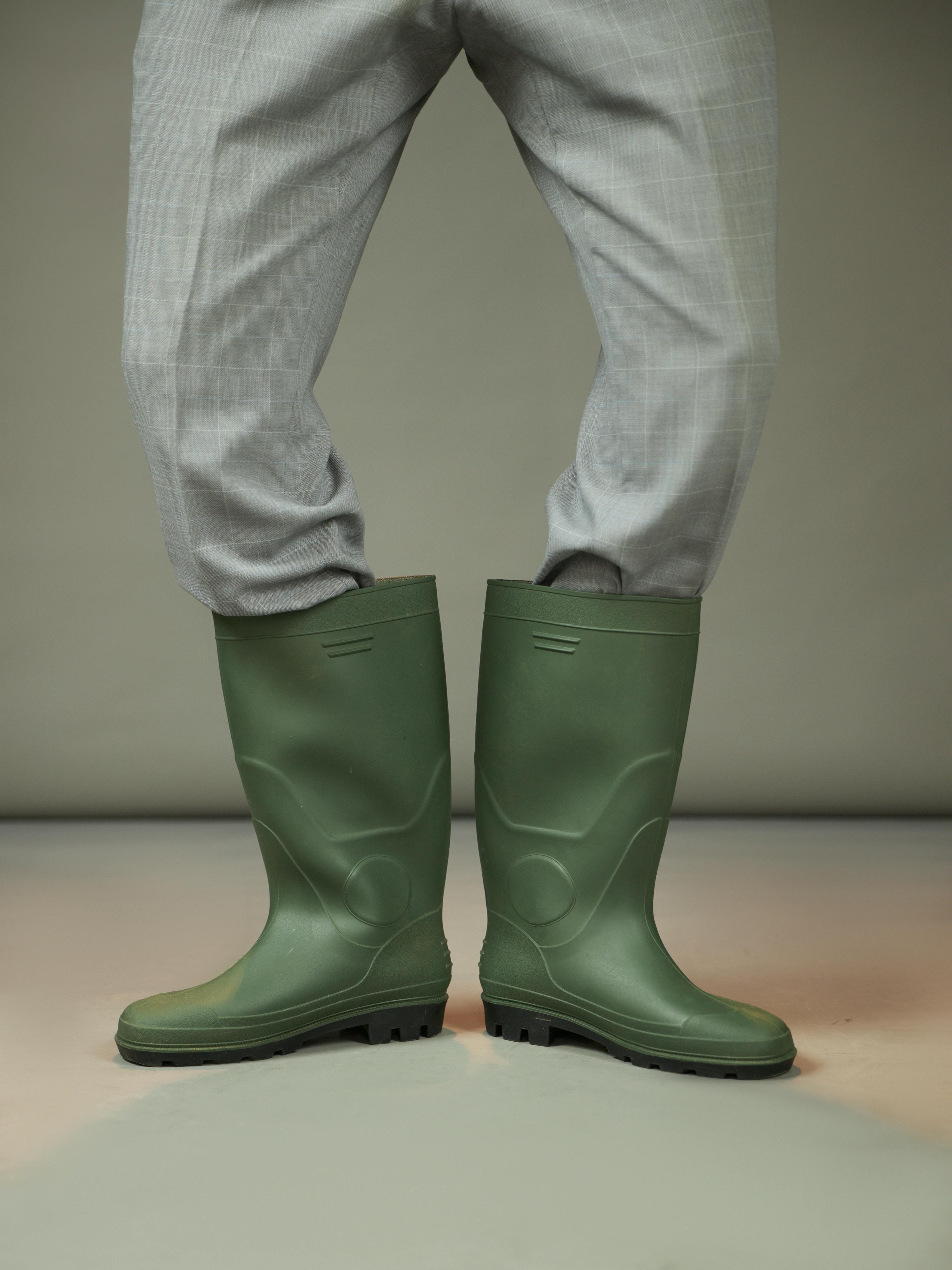 ingyenes Stílusos zöld gumicsizma szürke kockás nadrággal párosítva, modern divatkontrasztot képviselve. Stockfotó