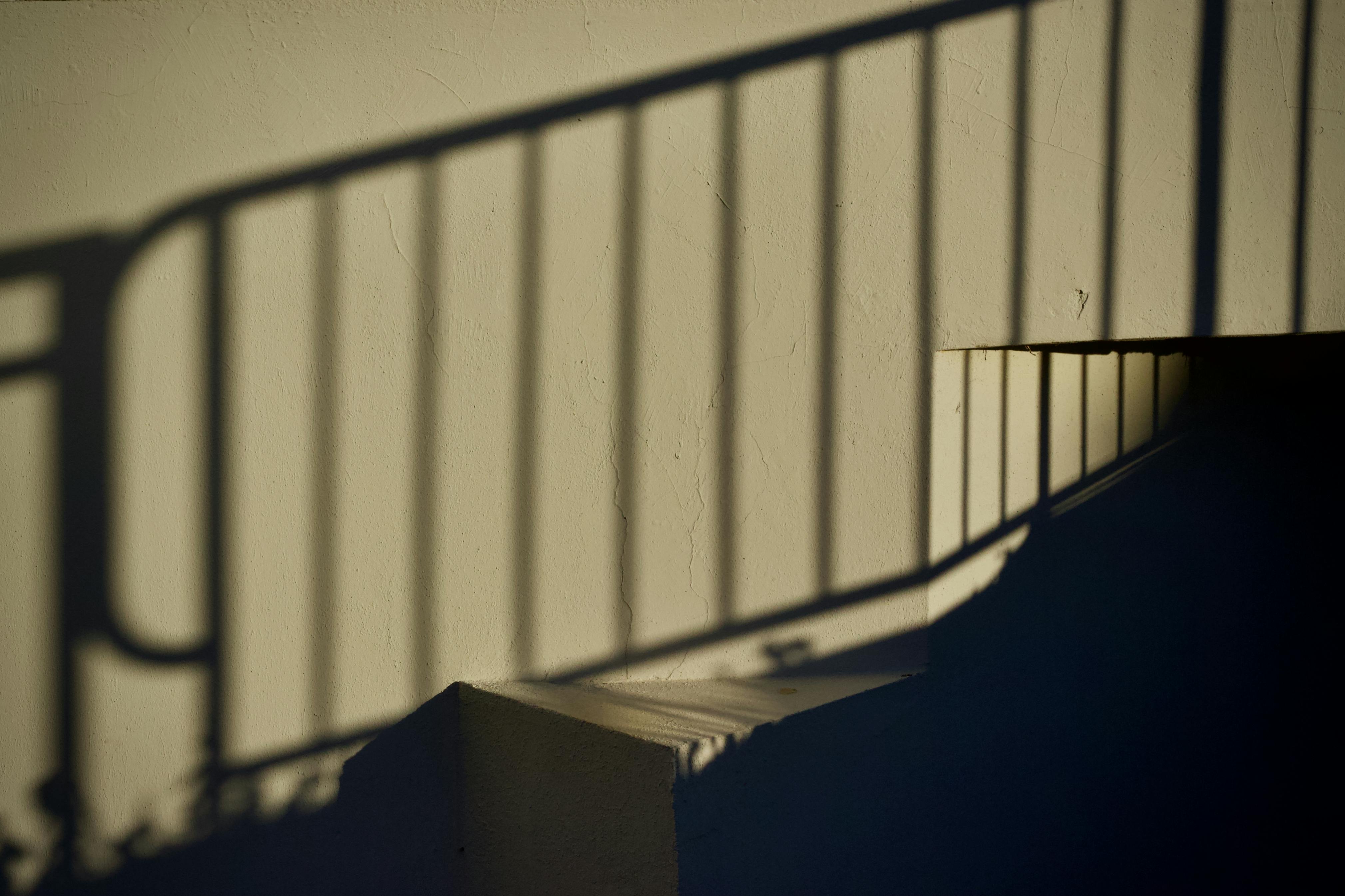 bezplatná Dramatické stíny zábradlí vytvářejí vzory na stěně schodiště. Základová fotografie