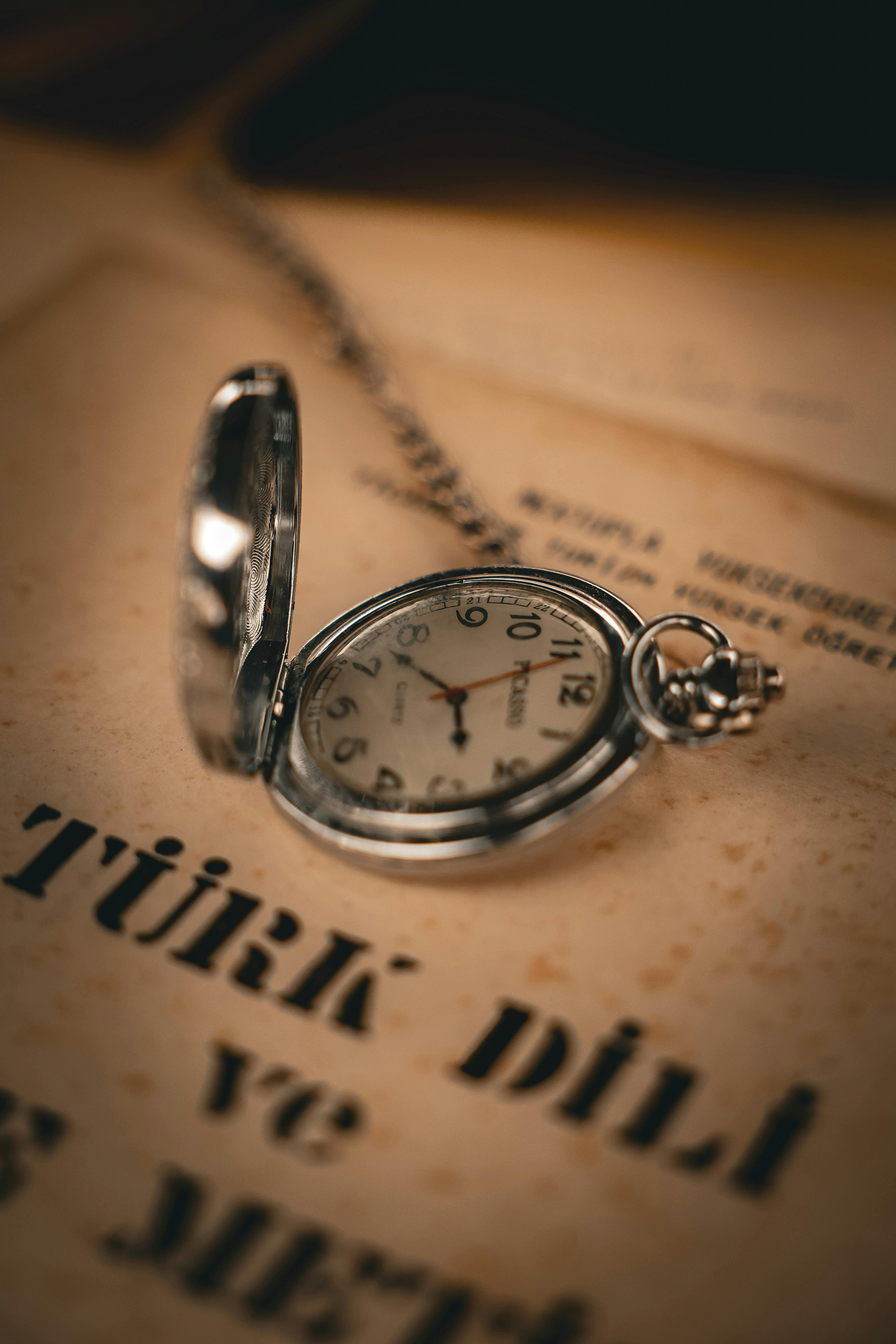 bezplatná Detailní záběr klasických kapesních hodinek položených na starém tureckém textovém papíře, evokující nostalgii. Základová fotografie