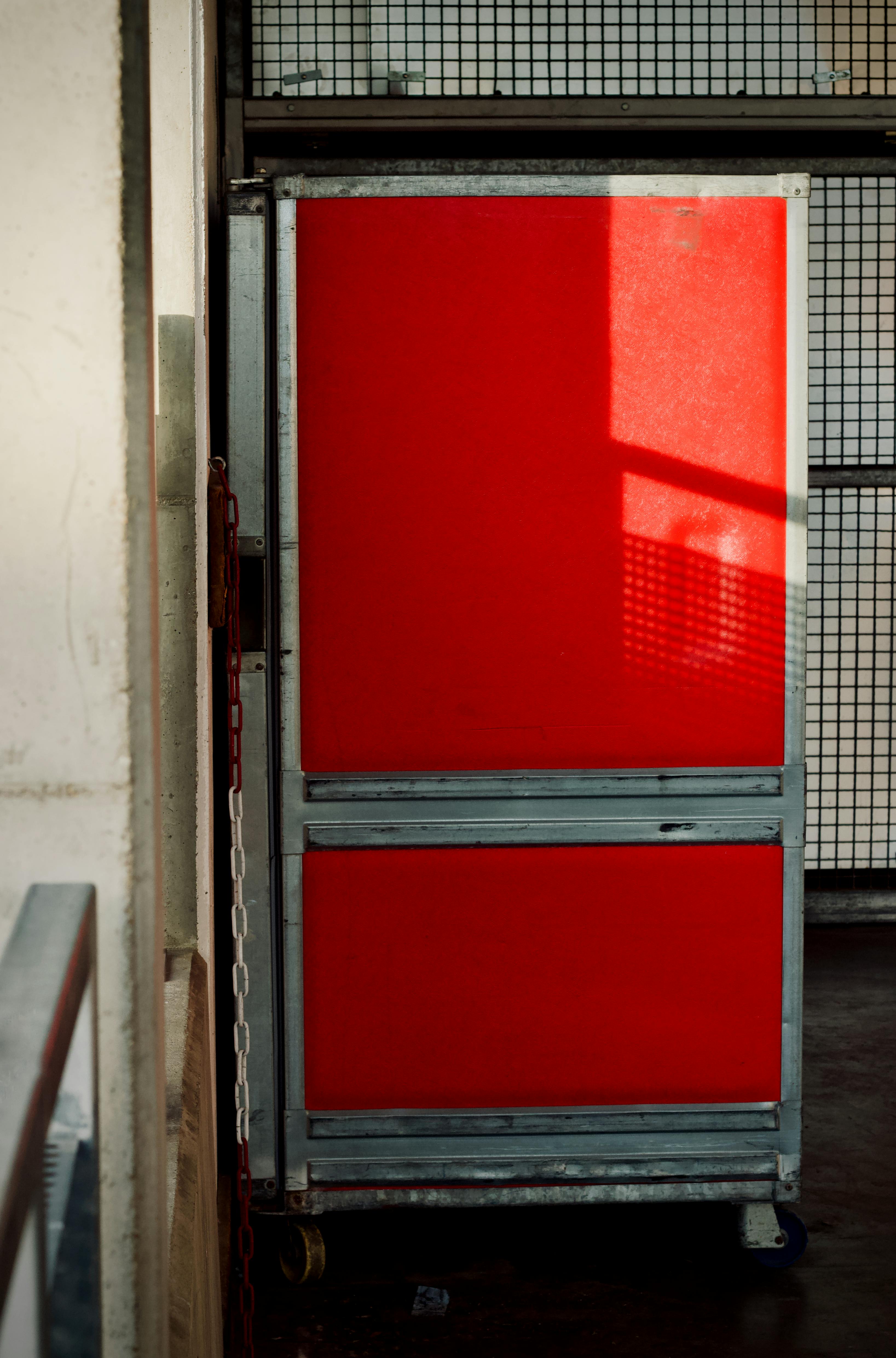 ingyenes Piros ipari tárolókonténer raktári környezetben, természetes fénnyel megvilágítva. Stockfotó