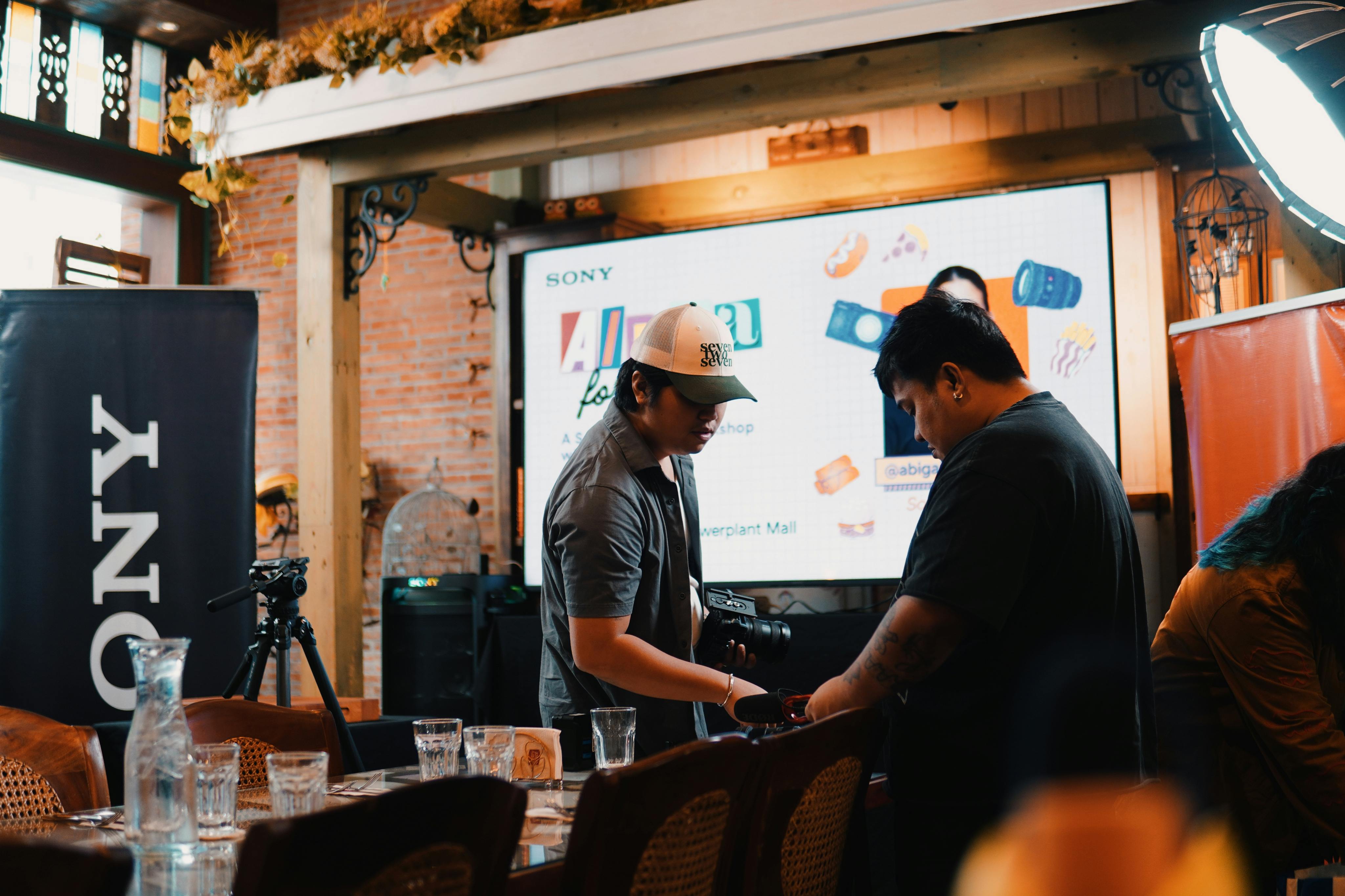 Two adults engage in a hands-on photography workshop with Sony equipment indoors.