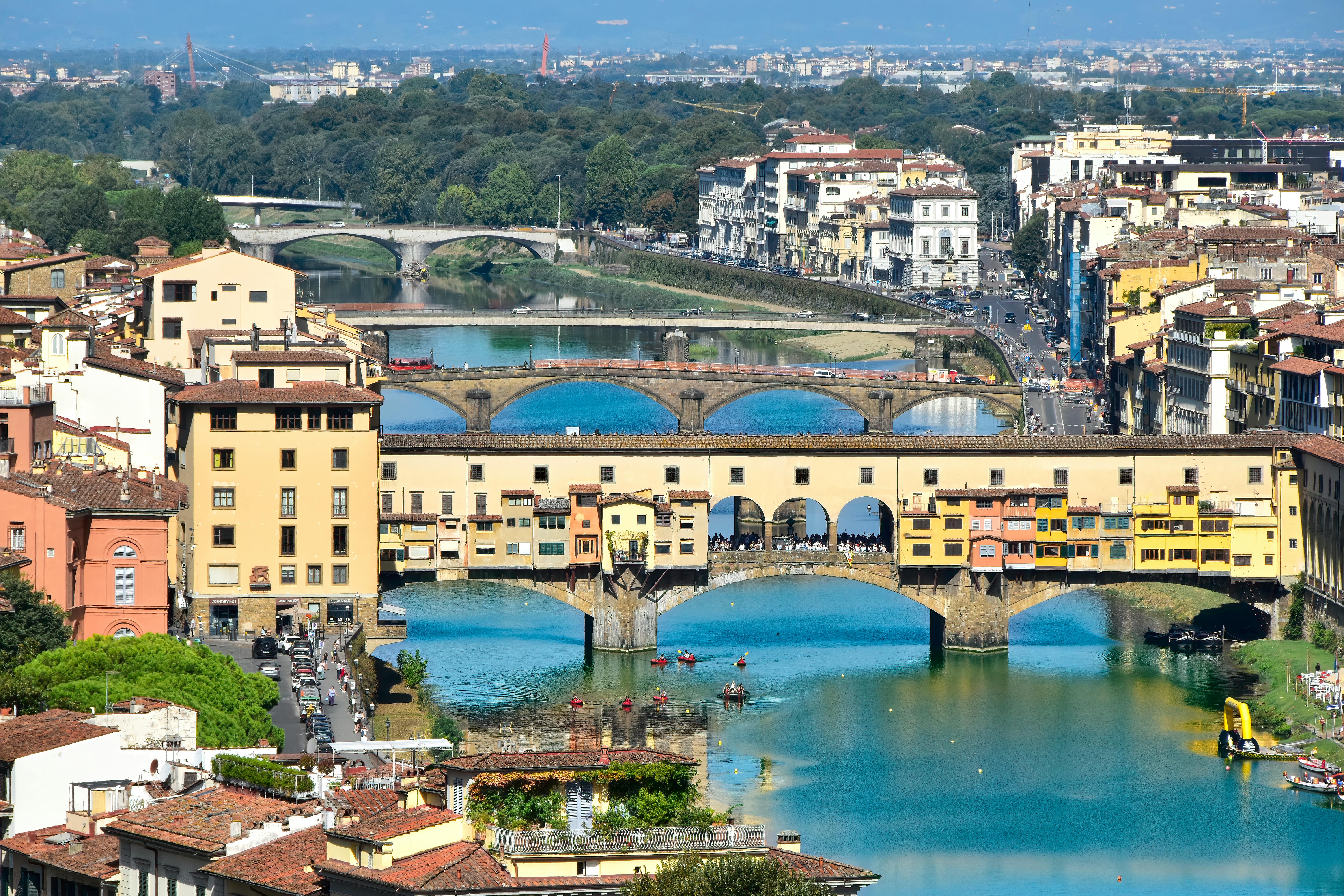 A scenic aerial view of Ponte Vecchio over the Arno River in Florence, Italy, showcasing colorful medieval architecture.