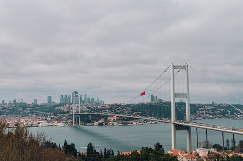 Free Panoramic view of the Bosphorus Bridge with Istanbul's skyline in the background, under a cloudy sky. Stock Photo
