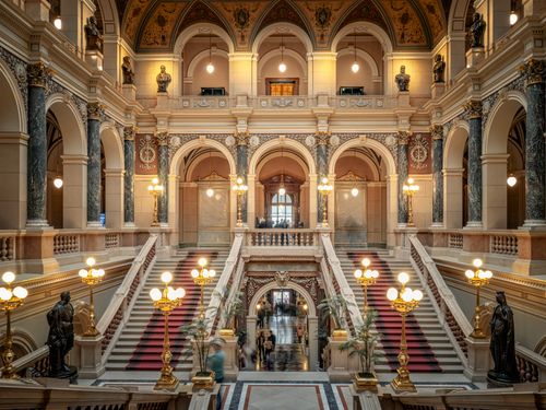 Free Elegant grand staircase of a historic European building with ornate architecture and statues. Stock Photo