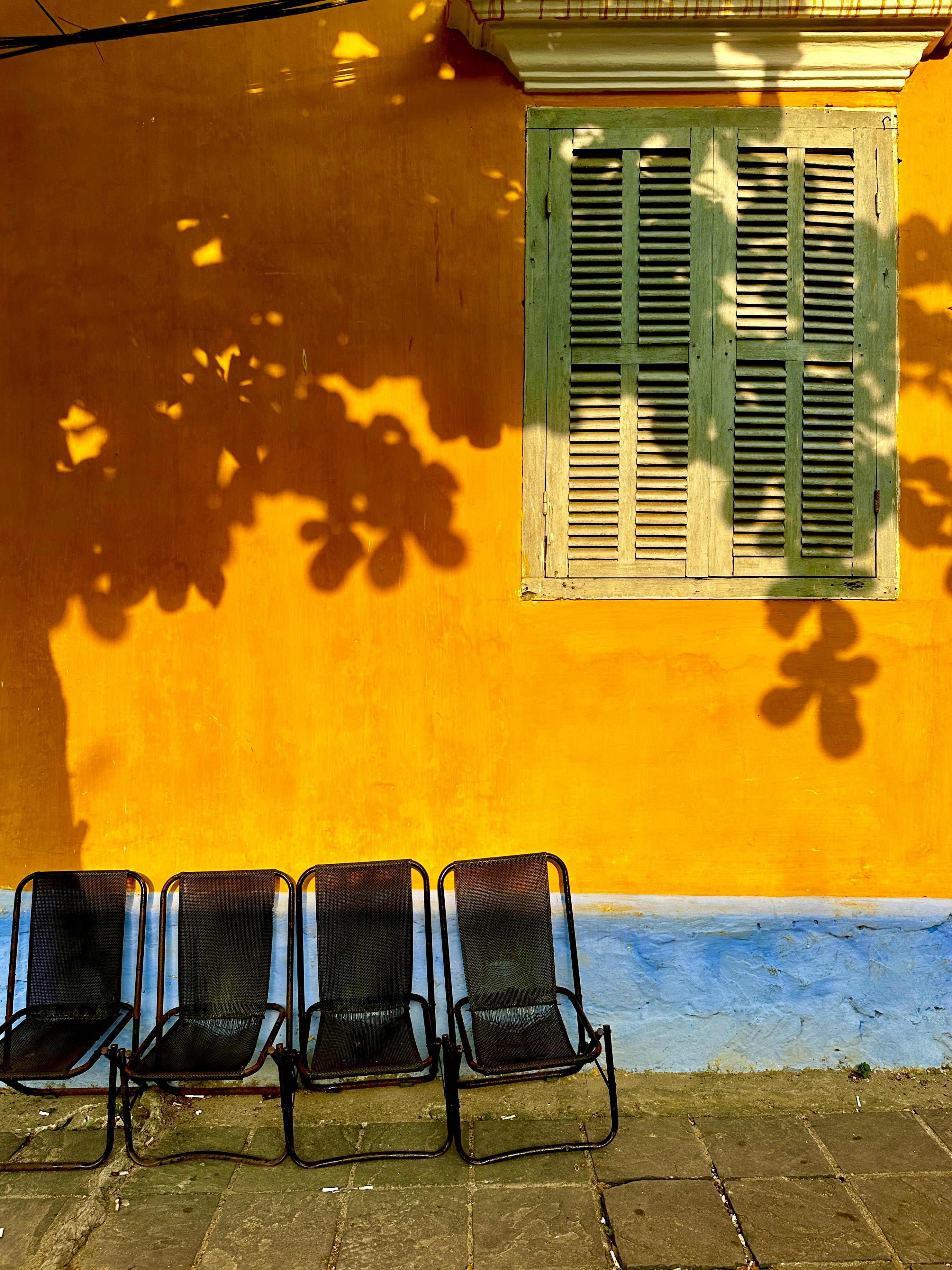 ฟรี กำแพงสไตล์เวียดนามร่วมสมัยที่ตกแต่งด้วยเงาและเก้าอี้ แสดงให้เห็นถึงสีสันสดใสในเมืองดานัง คลังภาพถ่าย