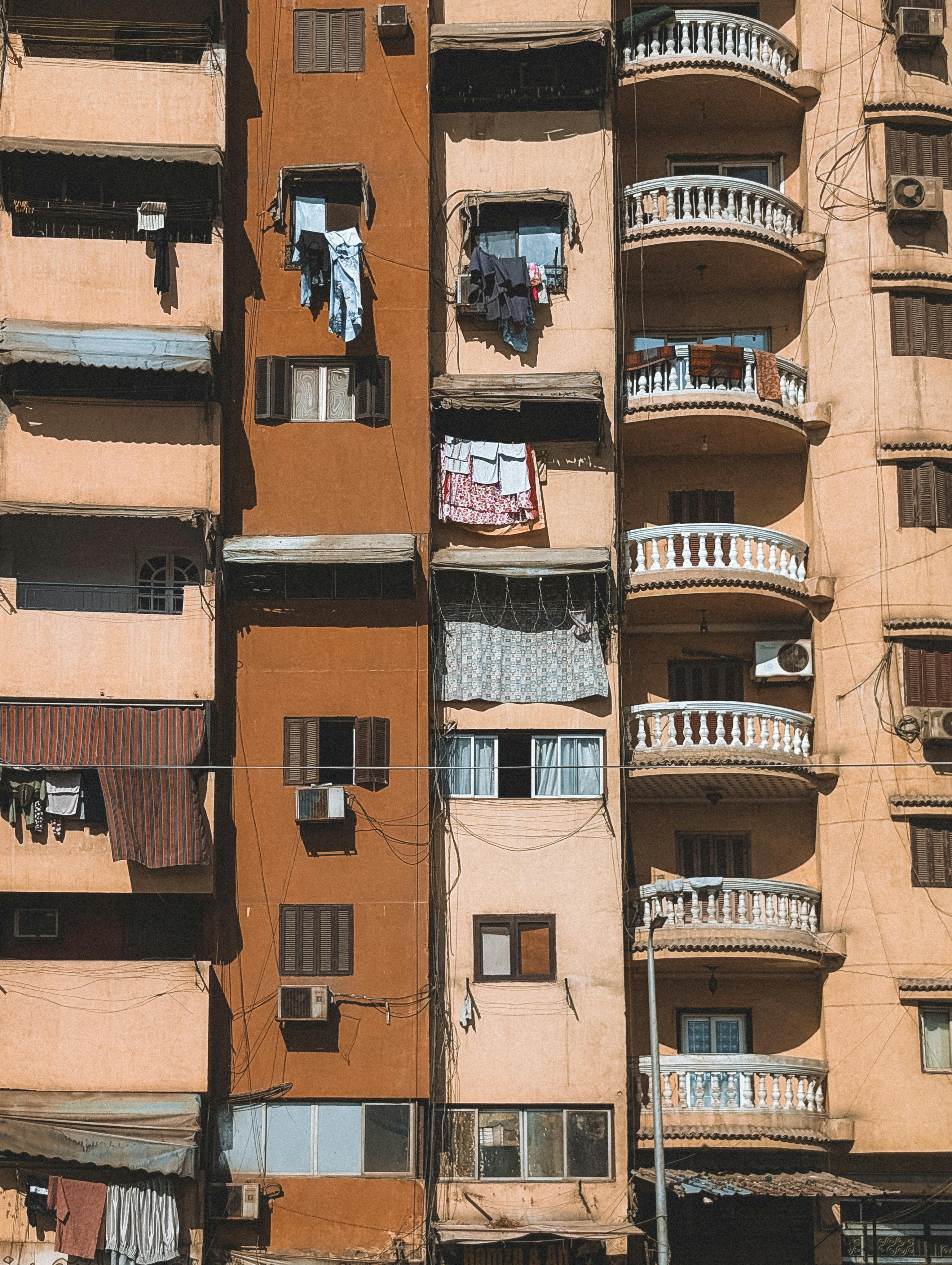 ฟรี ภาพมุมมองที่สดใสของด้านหน้าอาคารอพาร์ตเมนต์ในเมืองไคโร เผยให้เห็นรายละเอียดทางสถาปัตยกรรมและชีวิตประจำวัน คลังภาพถ่าย