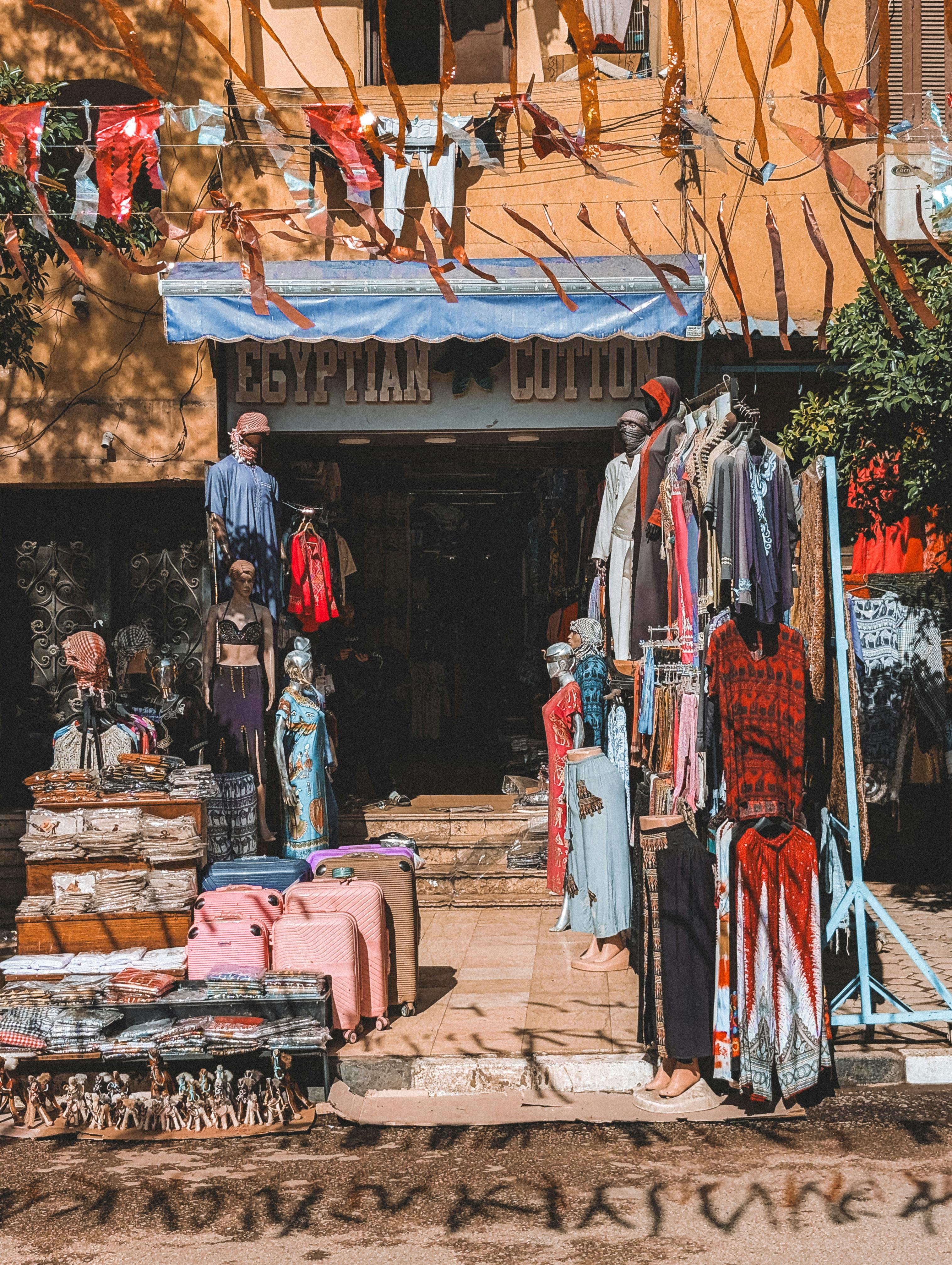 무료 번화한 카이로 거리 시장에 있는 이집트 면직물 가게에 진열된 다채로운 옷들. 스톡 사진