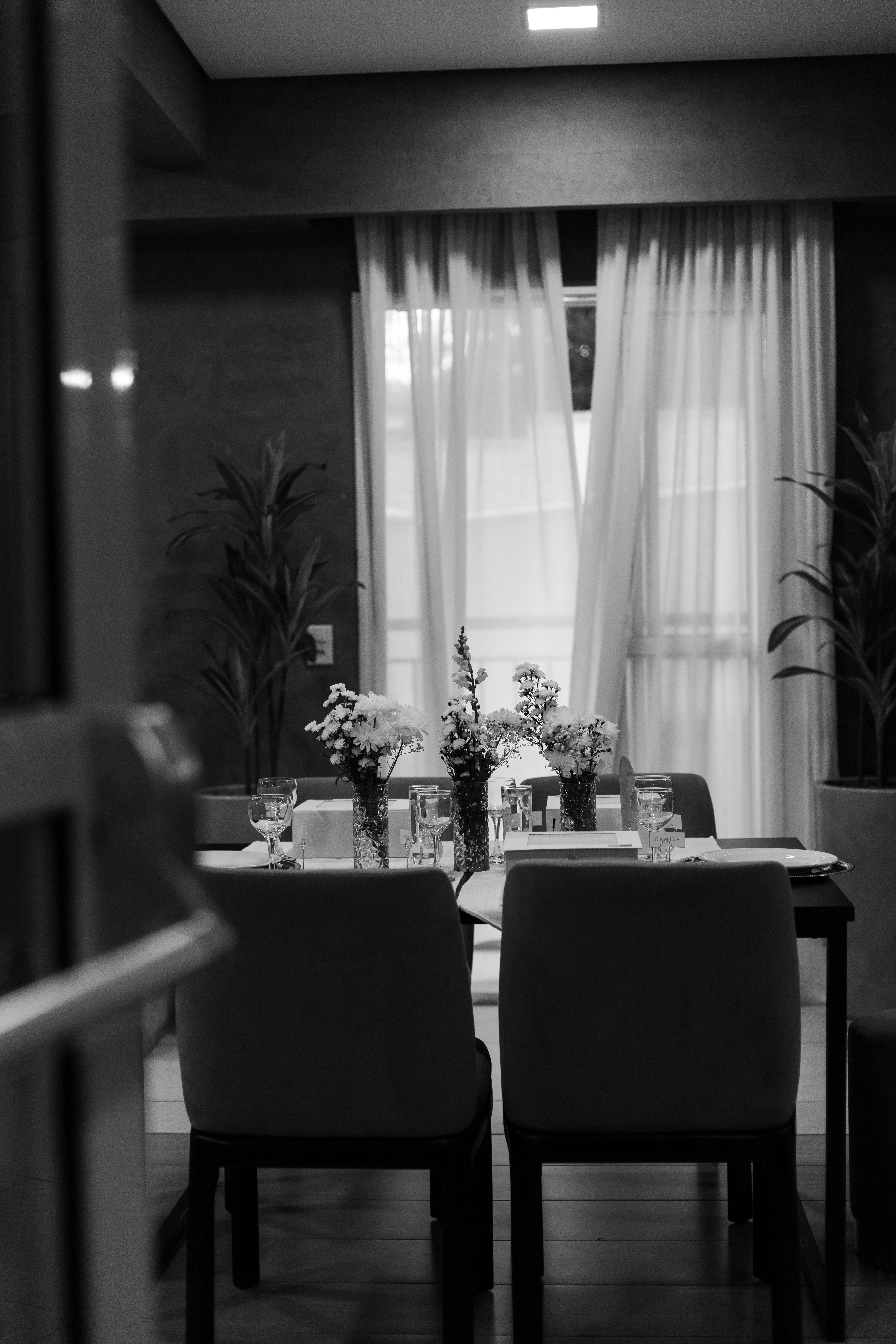 ingyenes Fekete-fehér fotó egy elegáns, virágdíszekkel díszített étkezőasztalról, amely tökéletes meghitt összejövetelekhez. Stockfotó