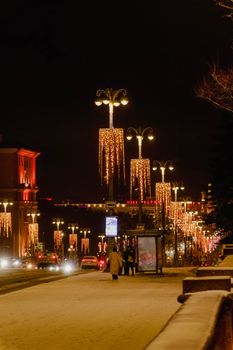 Night view of a street in Minsk adorned with festive lights, creating a warm and inviting atmosphere.