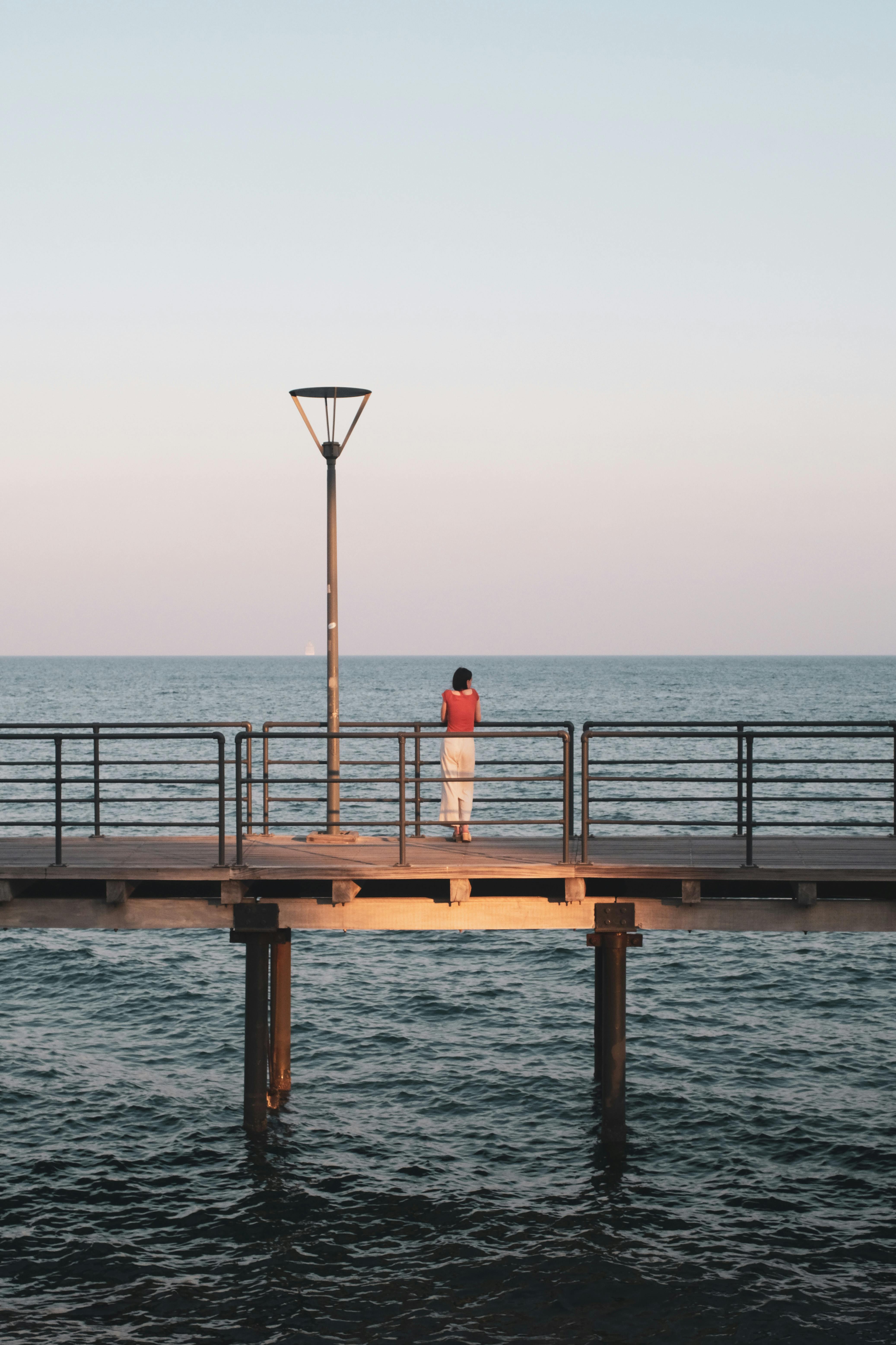 Miễn phí Một khung cảnh thanh bình của một người cô đơn trên cầu tàu lúc hoàng hôn ở Limassol, Síp, với biển và bầu trời tĩnh lặng. Ảnh lưu trữ