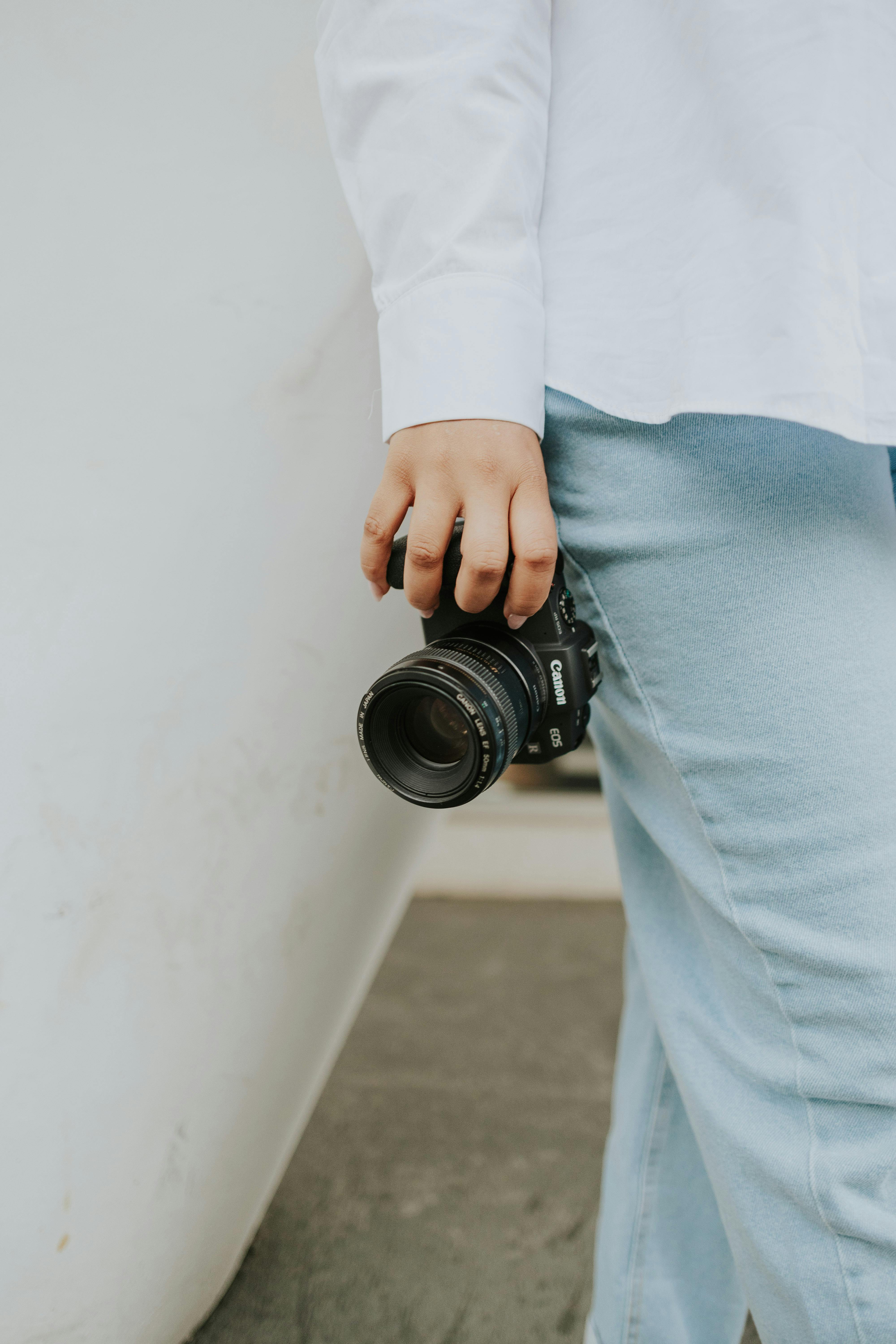 Zadarmo Osoba ležérne držiaca digitálnu zrkadlovku, ktorá zdôrazňuje moderný životný štýl fotografa. Fotka z fotobanky