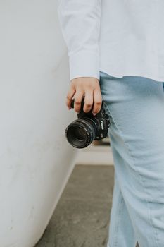 Person holding a DSLR camera casually, highlighting modern photography lifestyle.